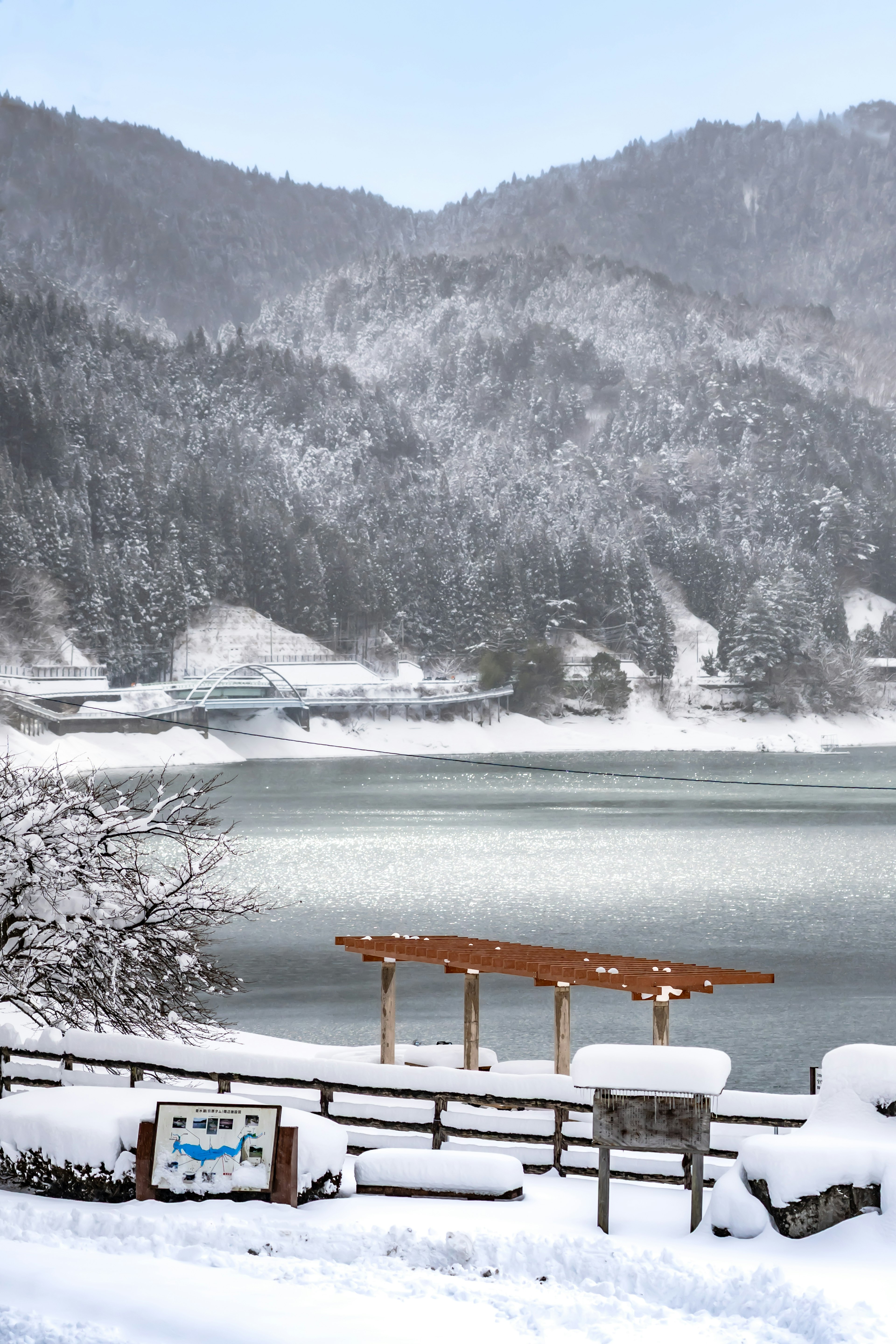 Lago y montañas cubiertos de nieve con un pequeño muelle de madera y un letrero