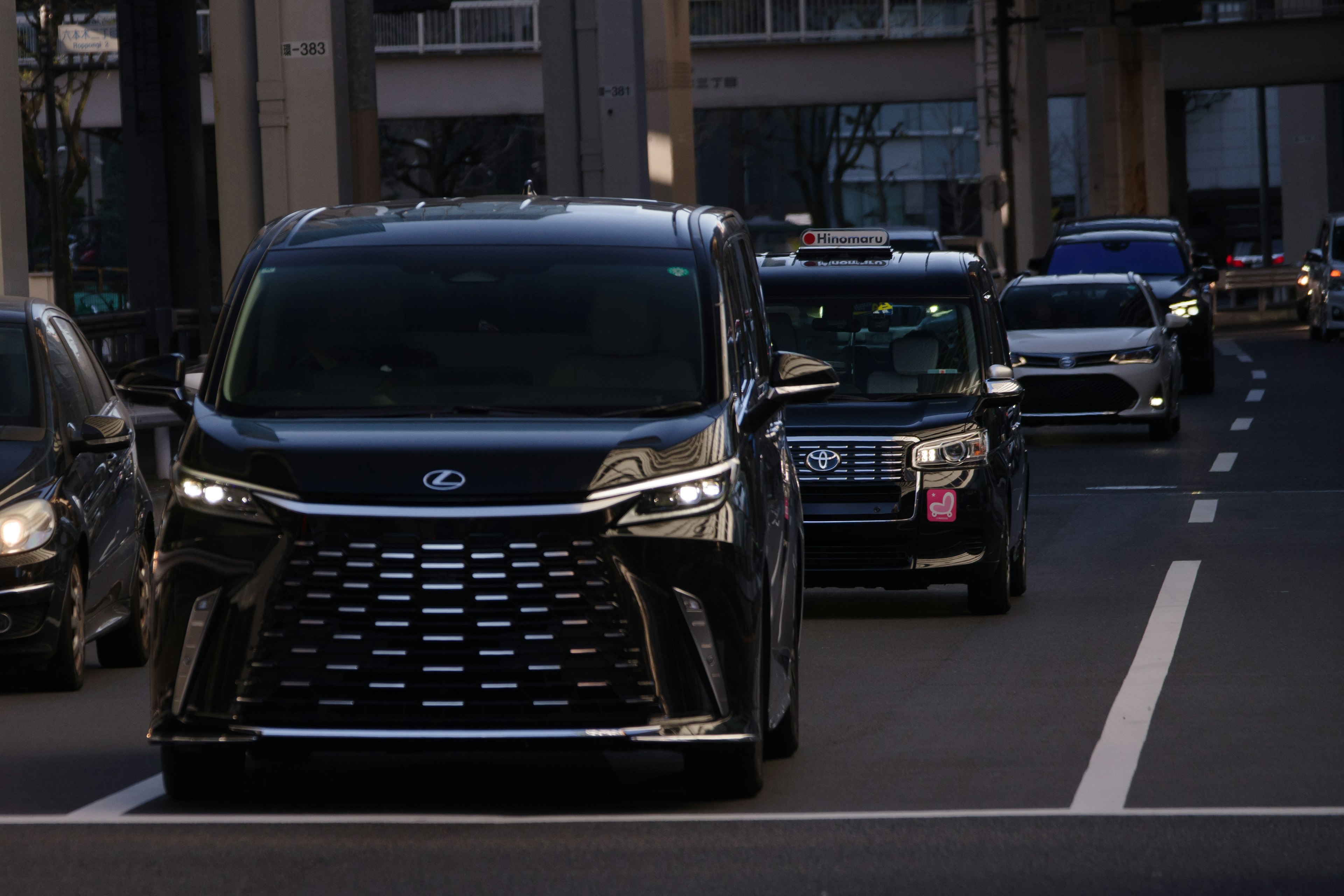 黒いミニバンが街中を走っている その後ろには他の車も見える