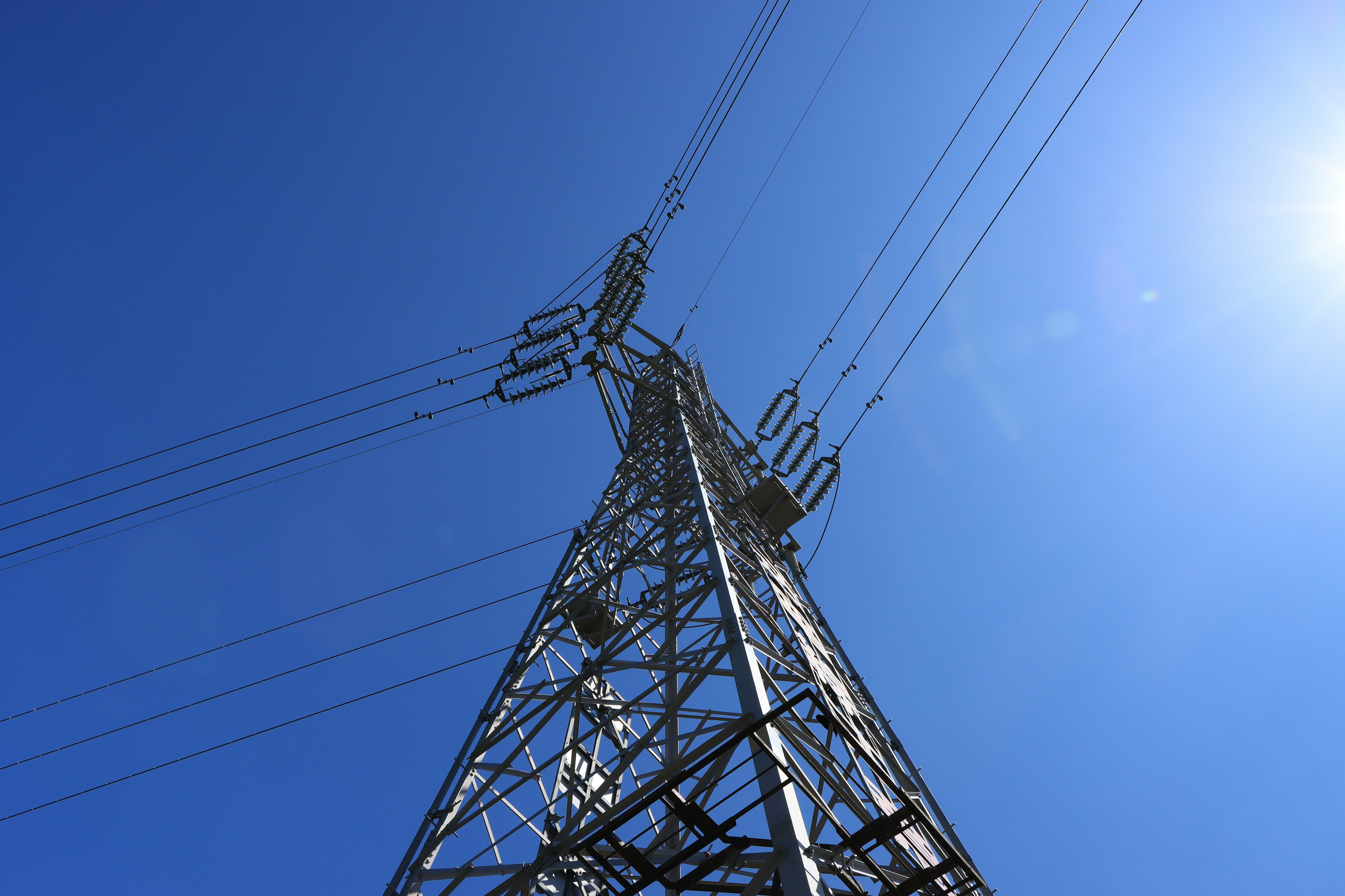 Foto de una torre de alta tensión bajo un cielo azul