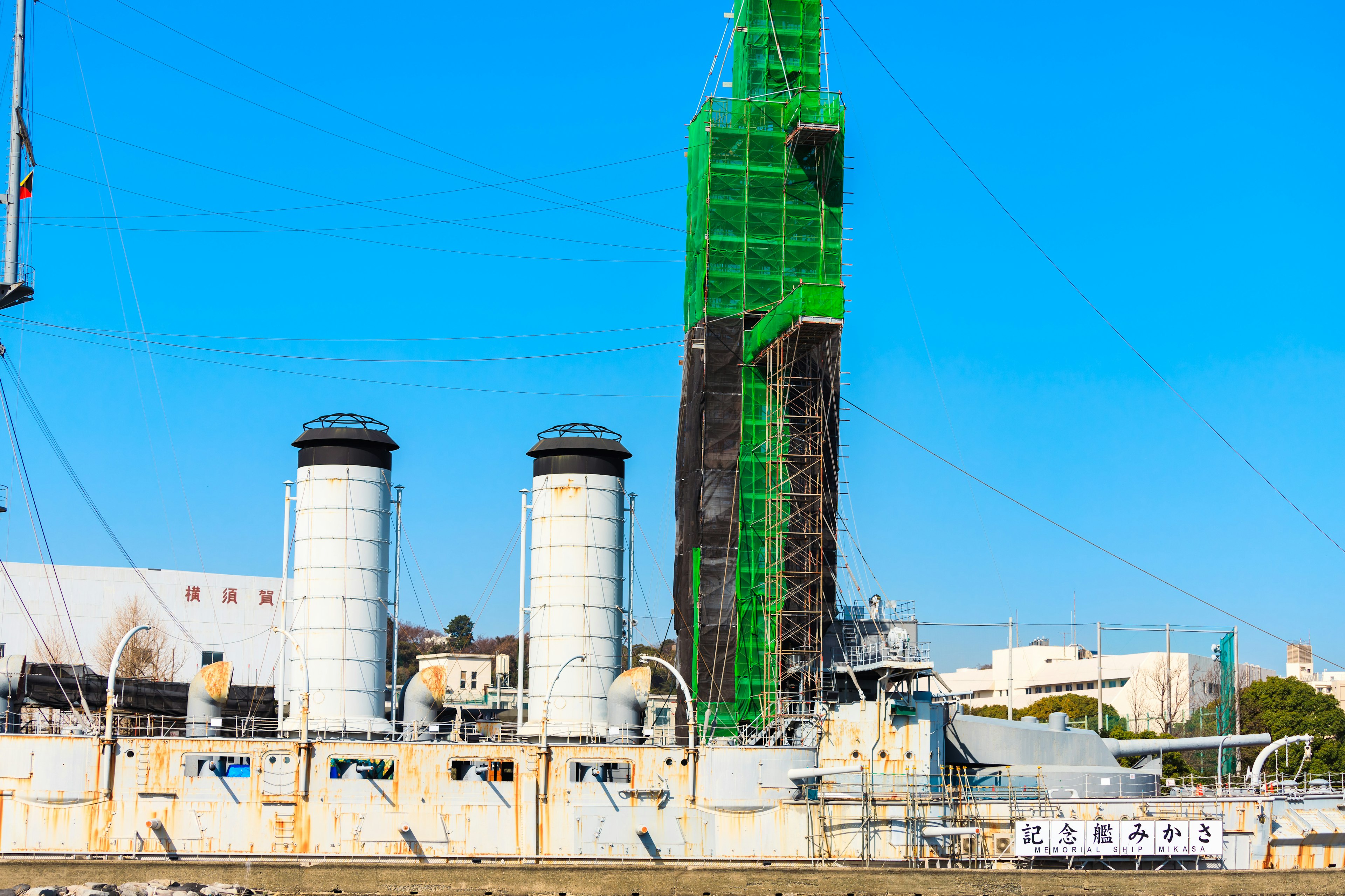 Ship docked at the harbor with a maintenance tower covered in green netting