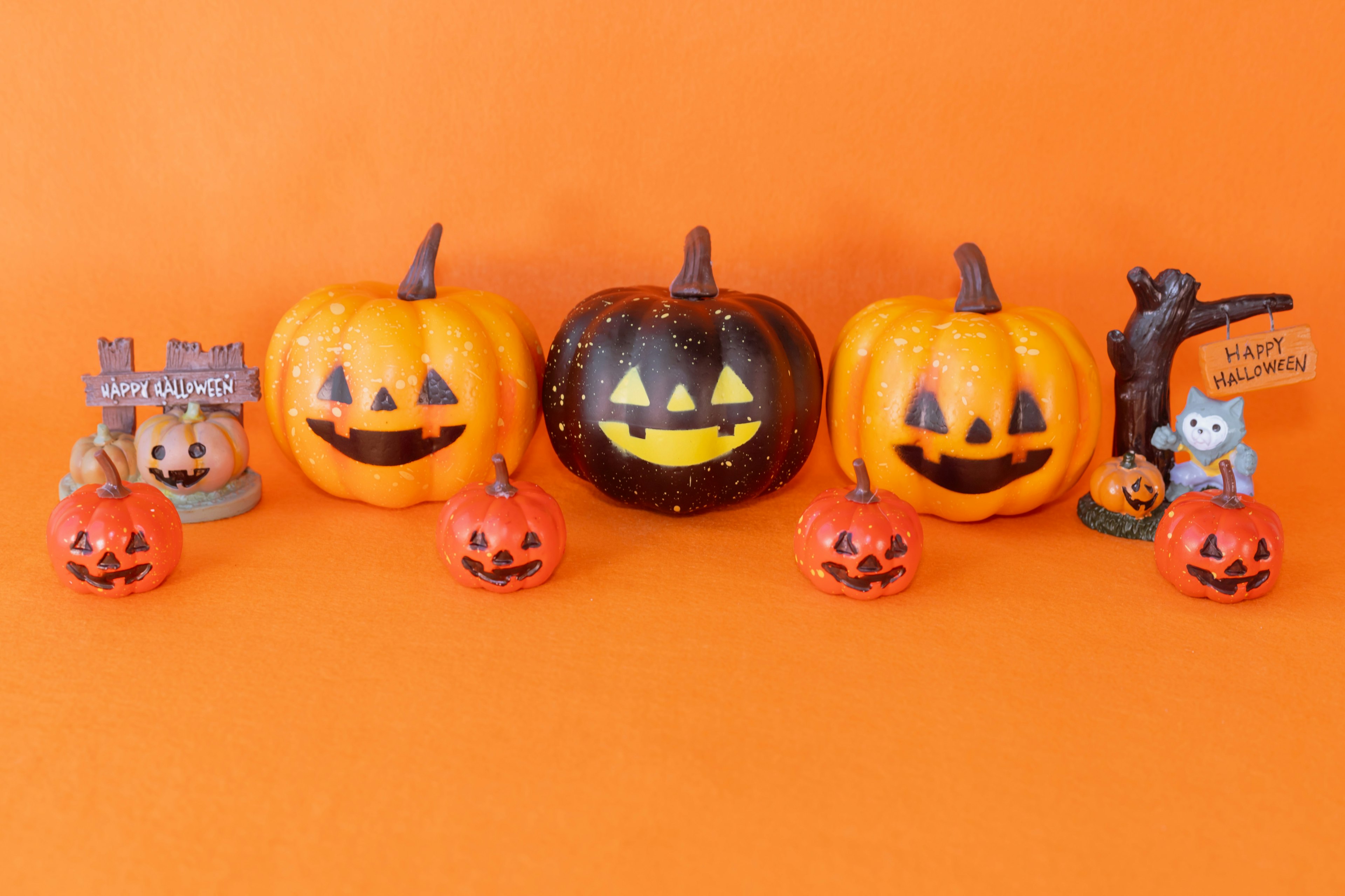 Calabazas y decoraciones de Halloween dispuestas sobre un fondo naranja