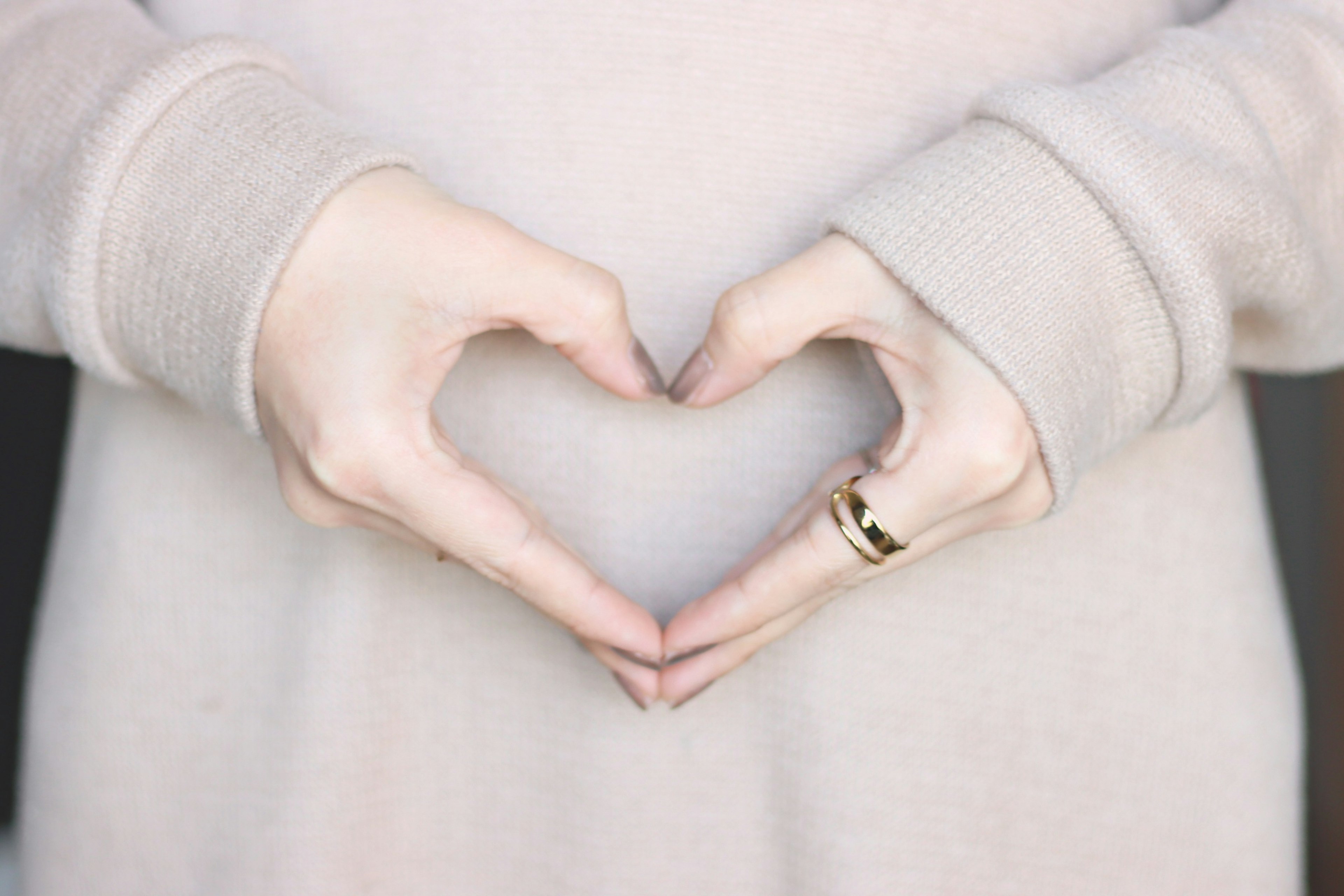 Hands forming a heart shape wearing a ring