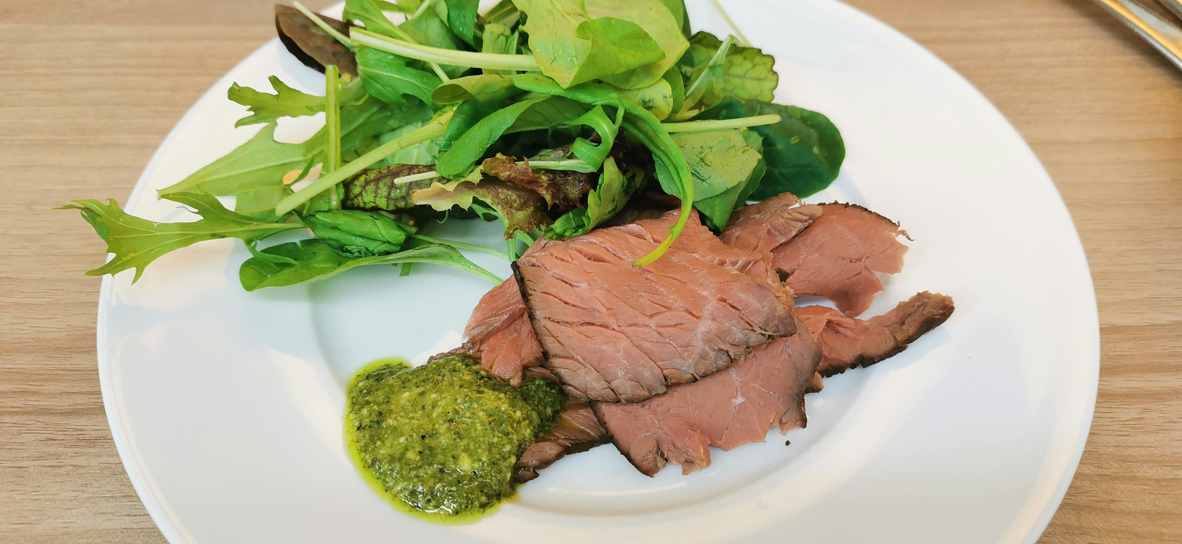 Scheiben von Rinderbraten mit frischem Salat auf einem weißen Teller