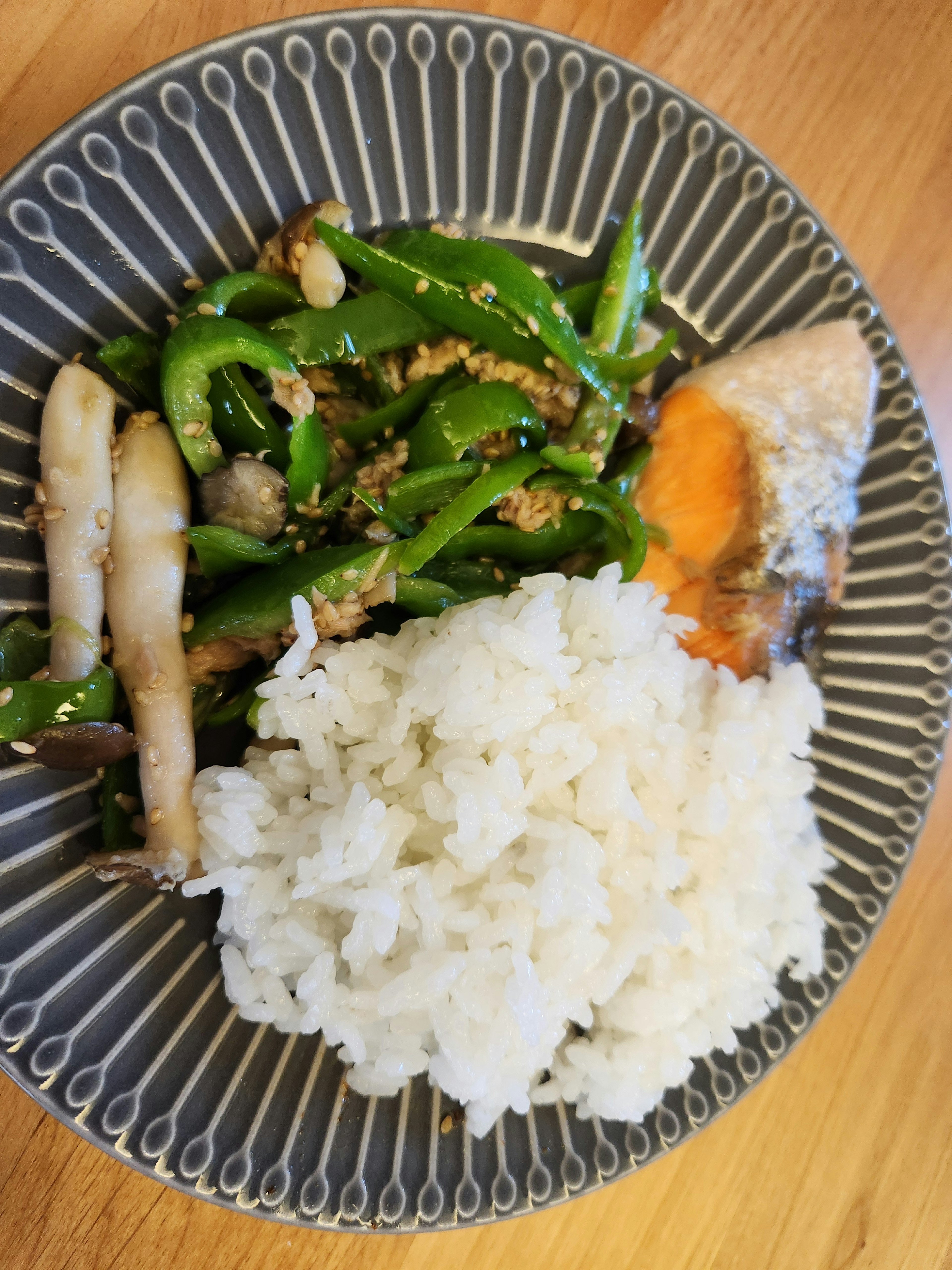 A plate of rice with green bell peppers and grilled fish