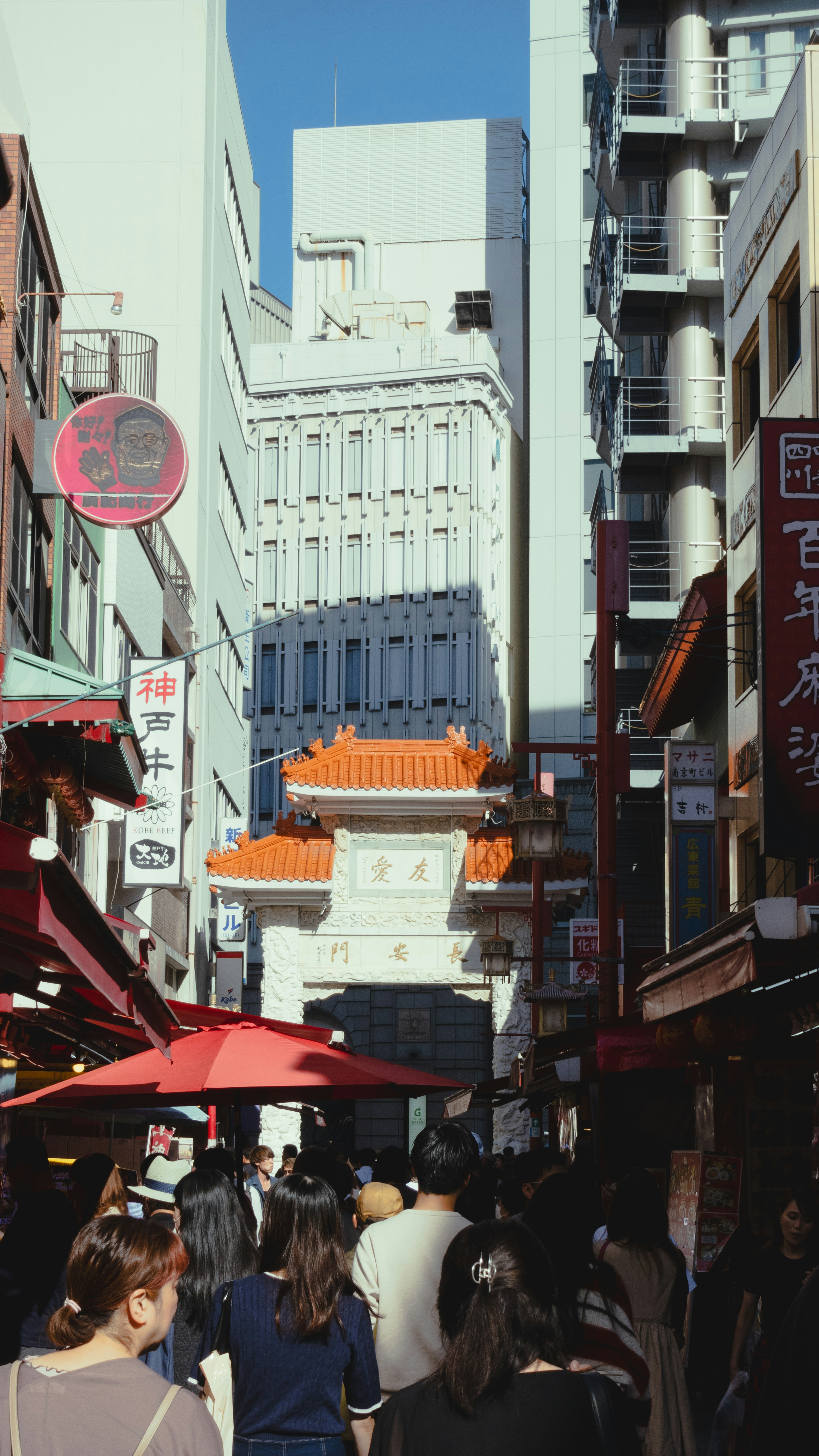 Busy street filled with people featuring a high-rise building and traditional arch