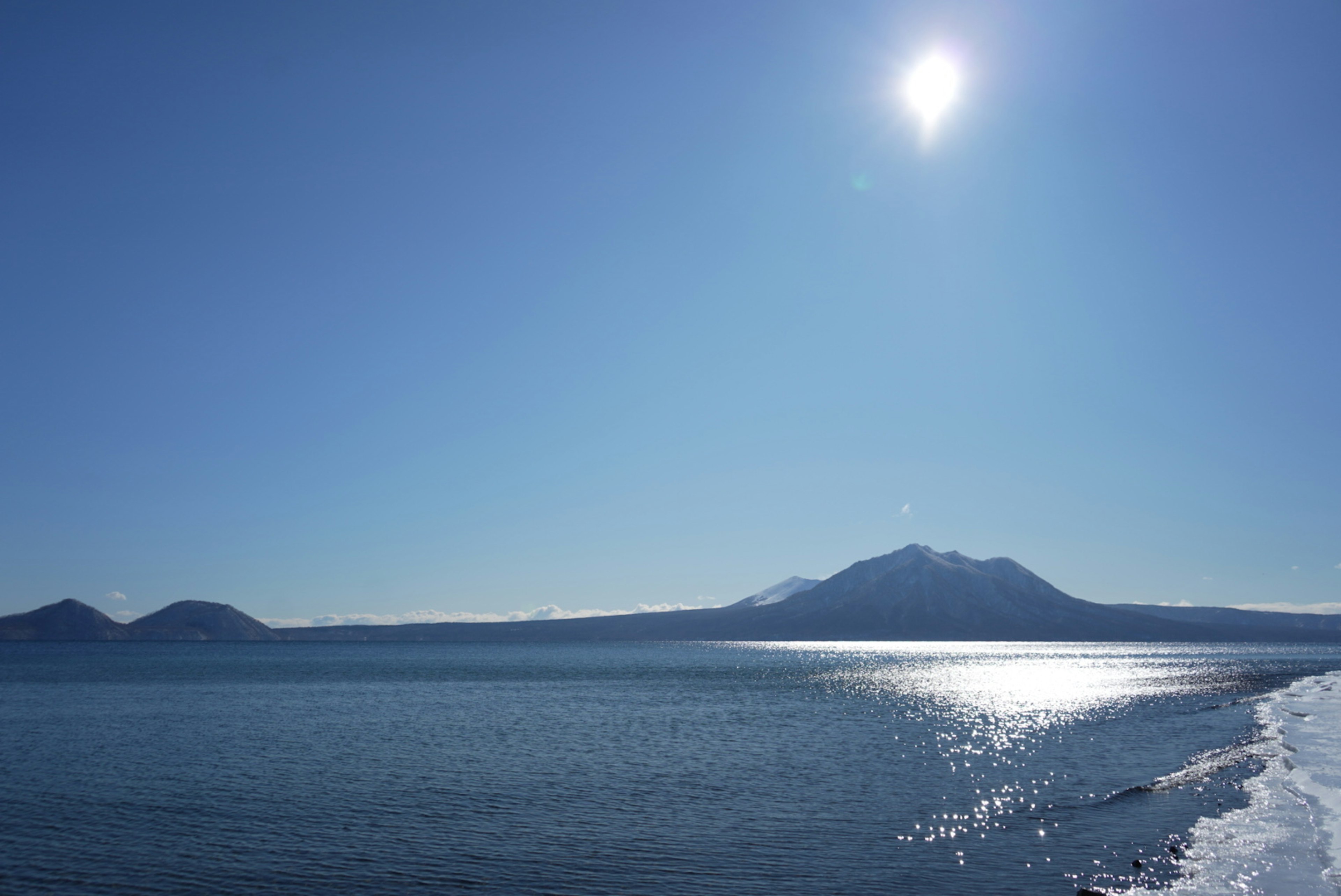 Cielo blu chiaro e vista sull'oceano, sole splendente, montagne in lontananza