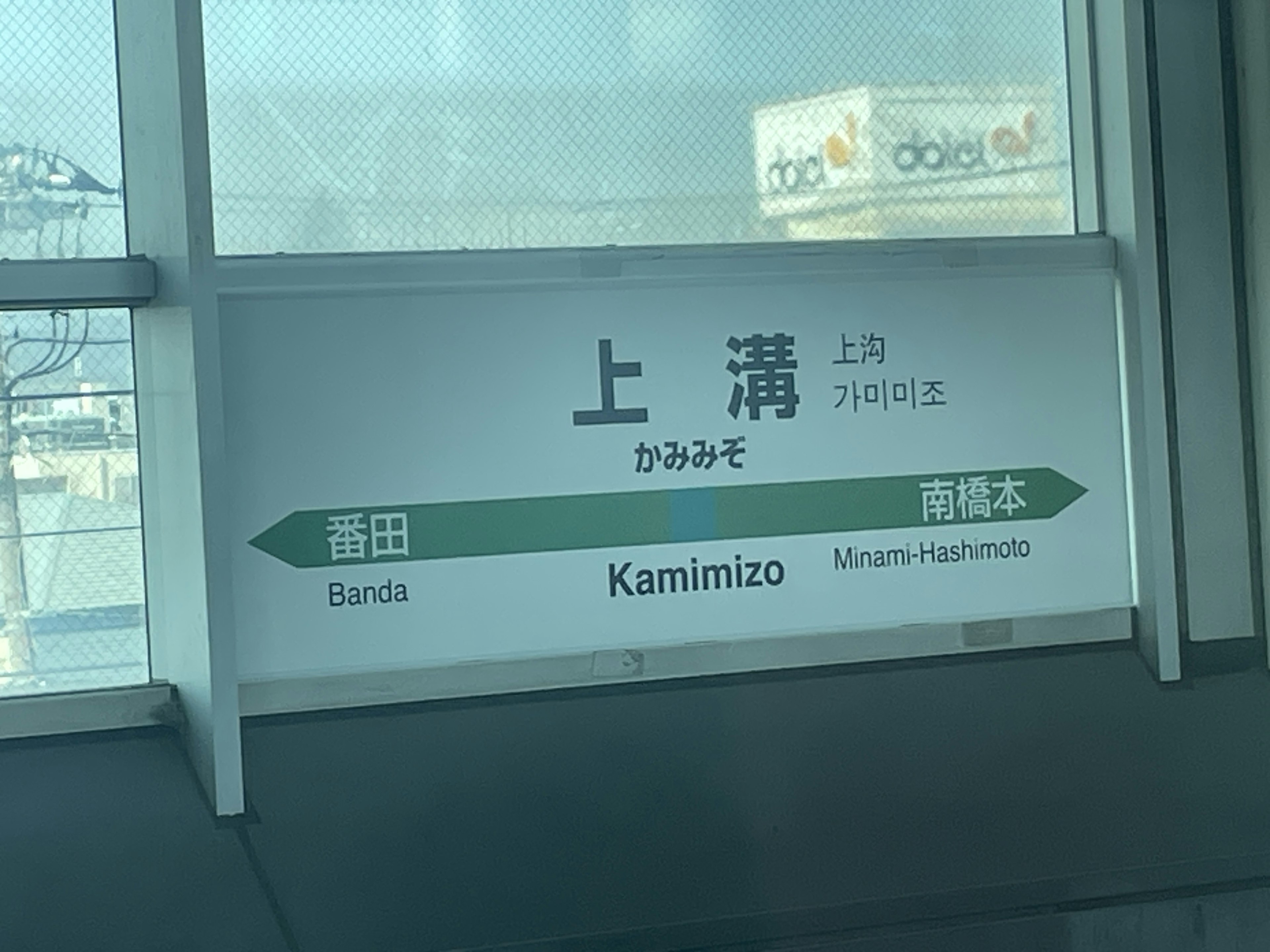 Station sign for Kamimizo Station displaying Japanese and English names