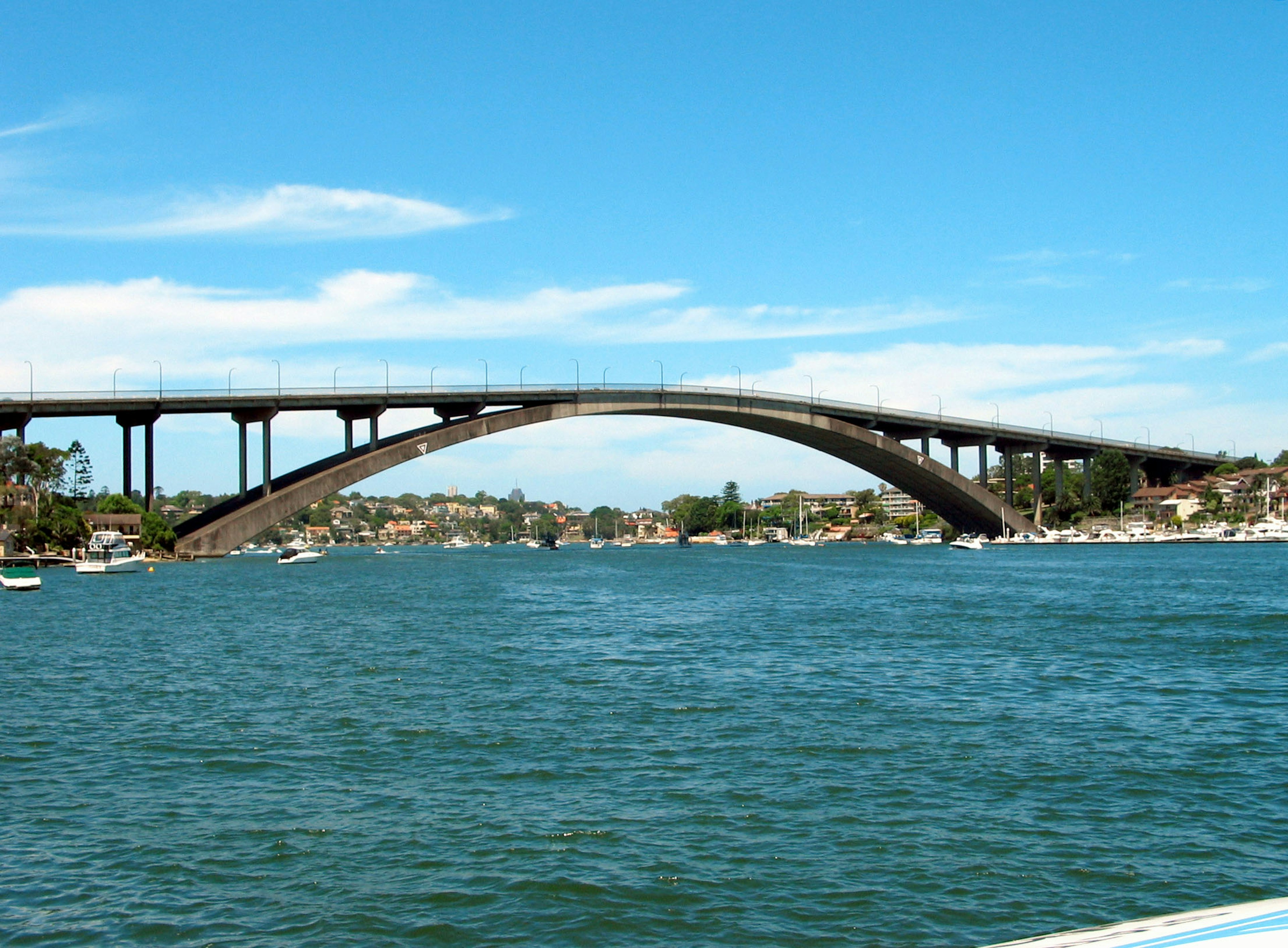 Ponte ad arco sopra acqua calma sotto un cielo blu