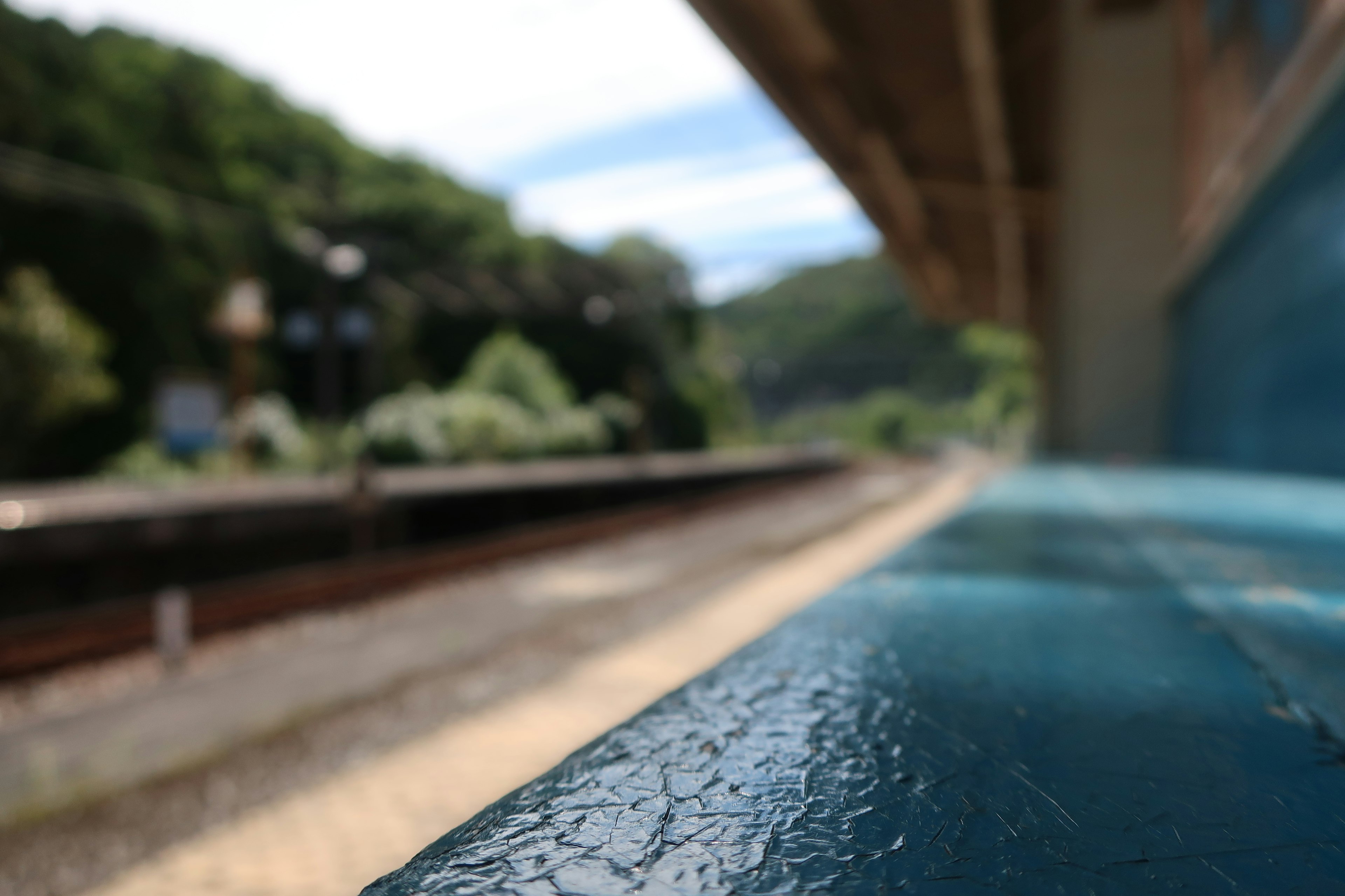 Blurred view of a train station with a blue bench in the foreground