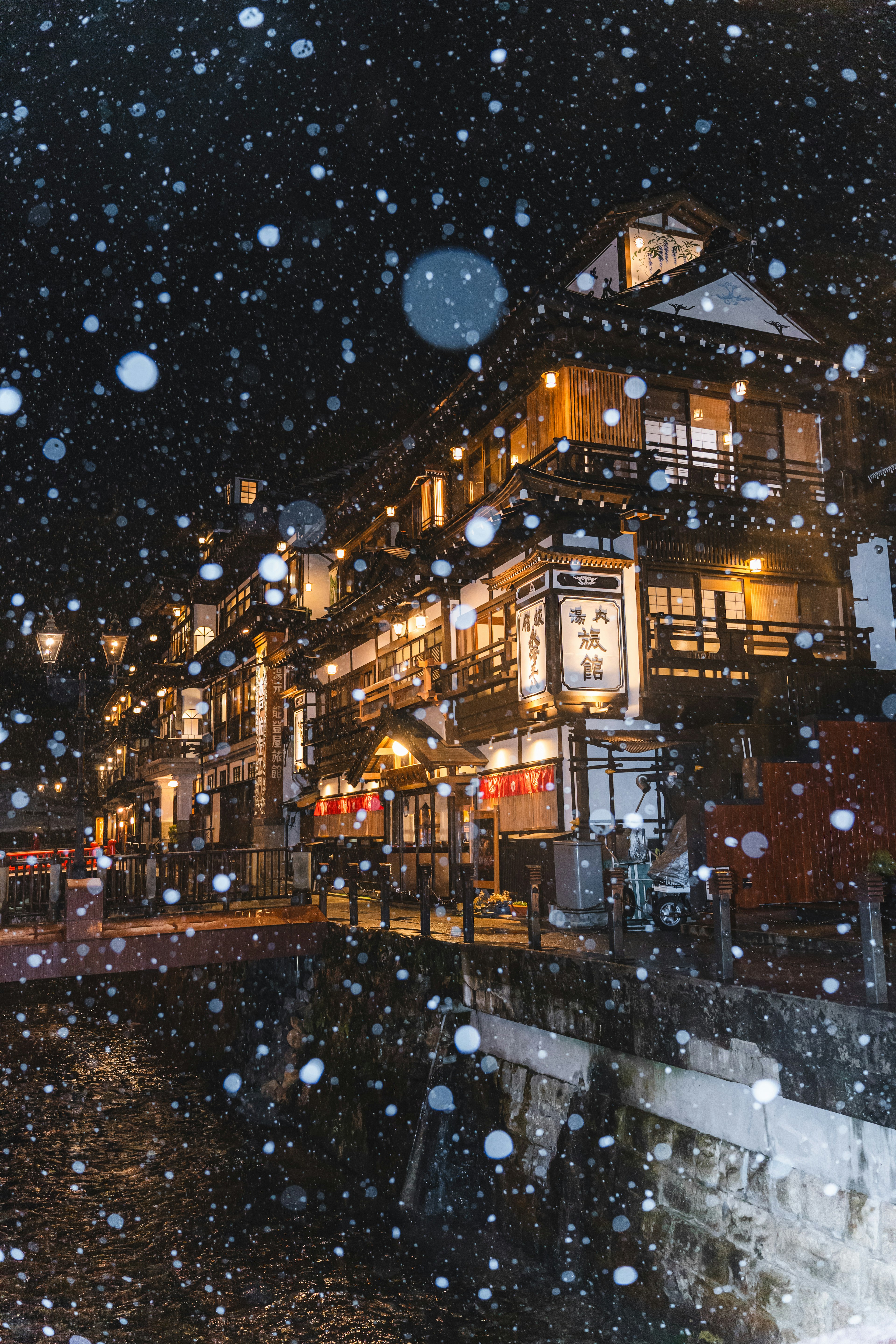 雪の降る夜に照明が輝く温泉街の風景