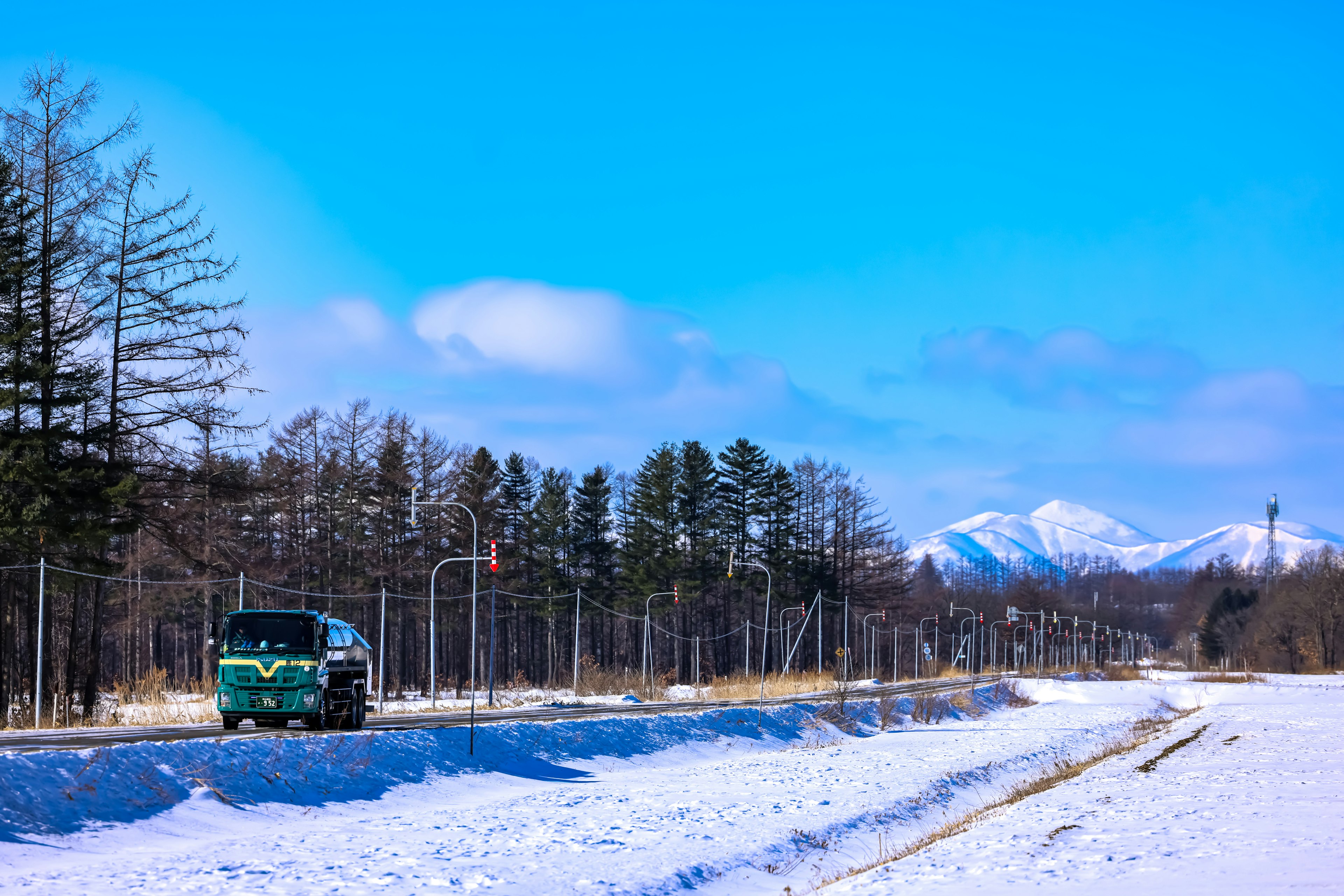 雪に覆われた風景に沿った緑のバスと山々