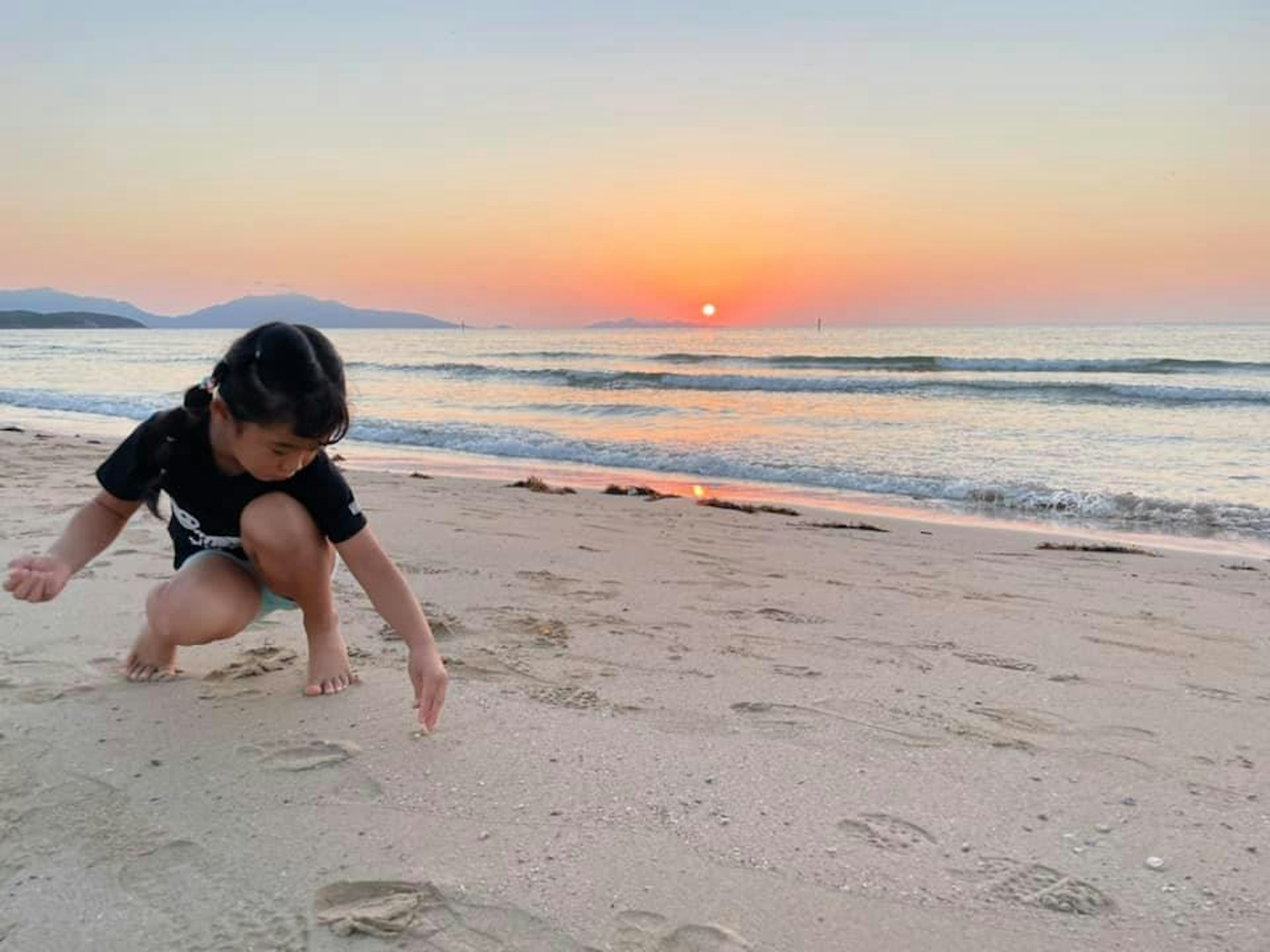 Enfant jouant dans le sable sur la plage au coucher de soleil