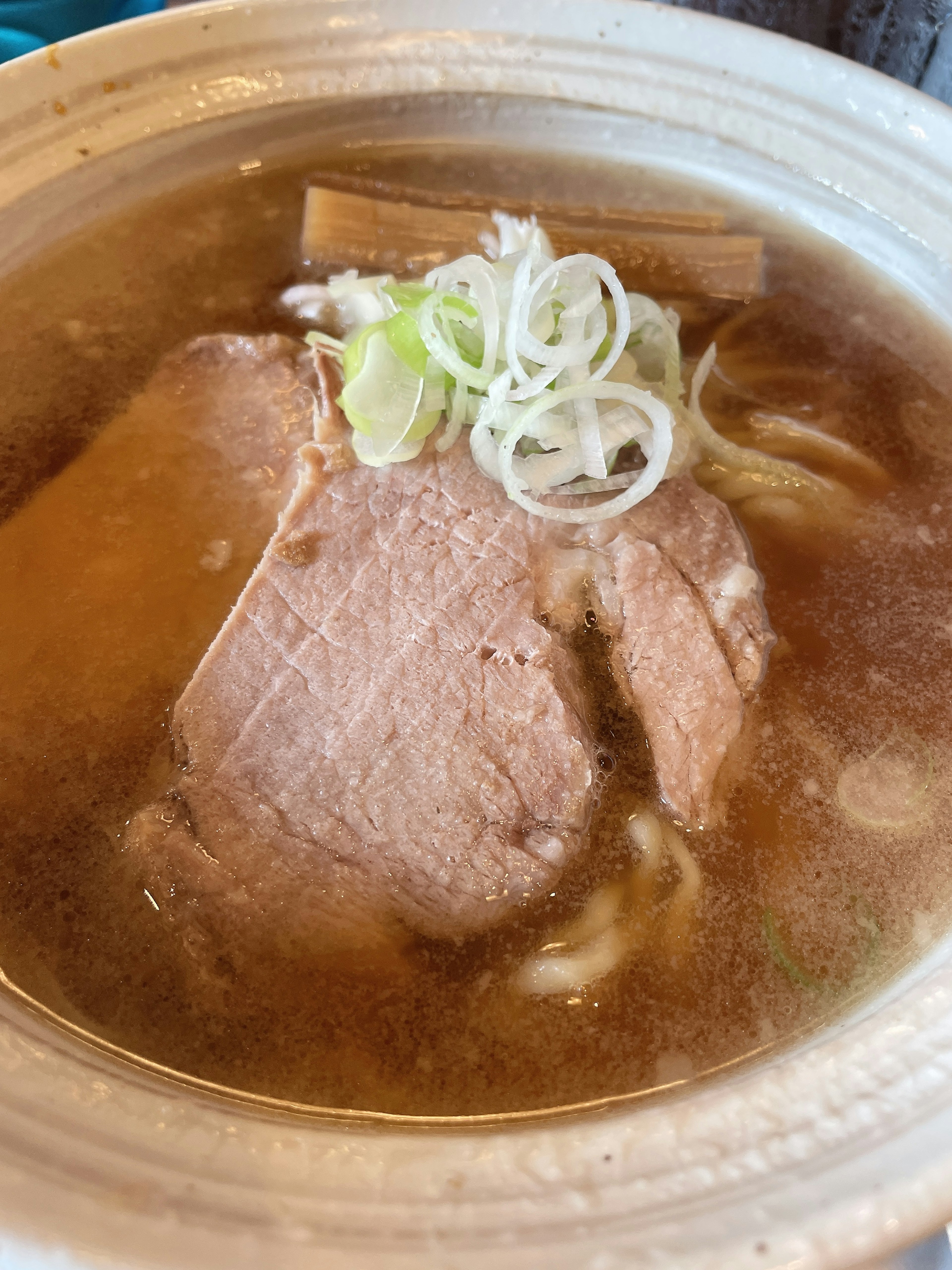 ラーメンのスープに浮かぶチャーシューとネギ