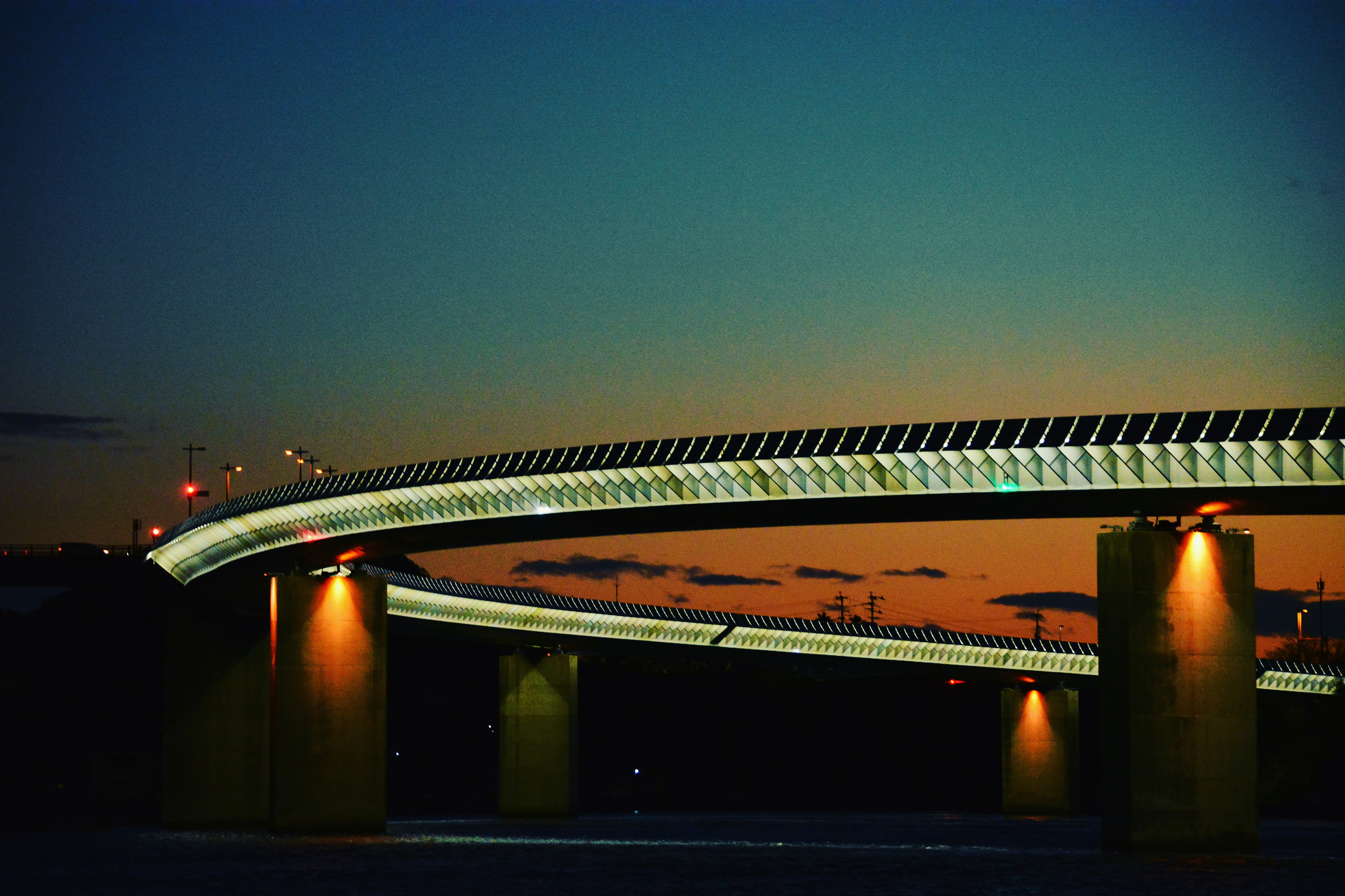 Curved bridge with lights against a twilight sky