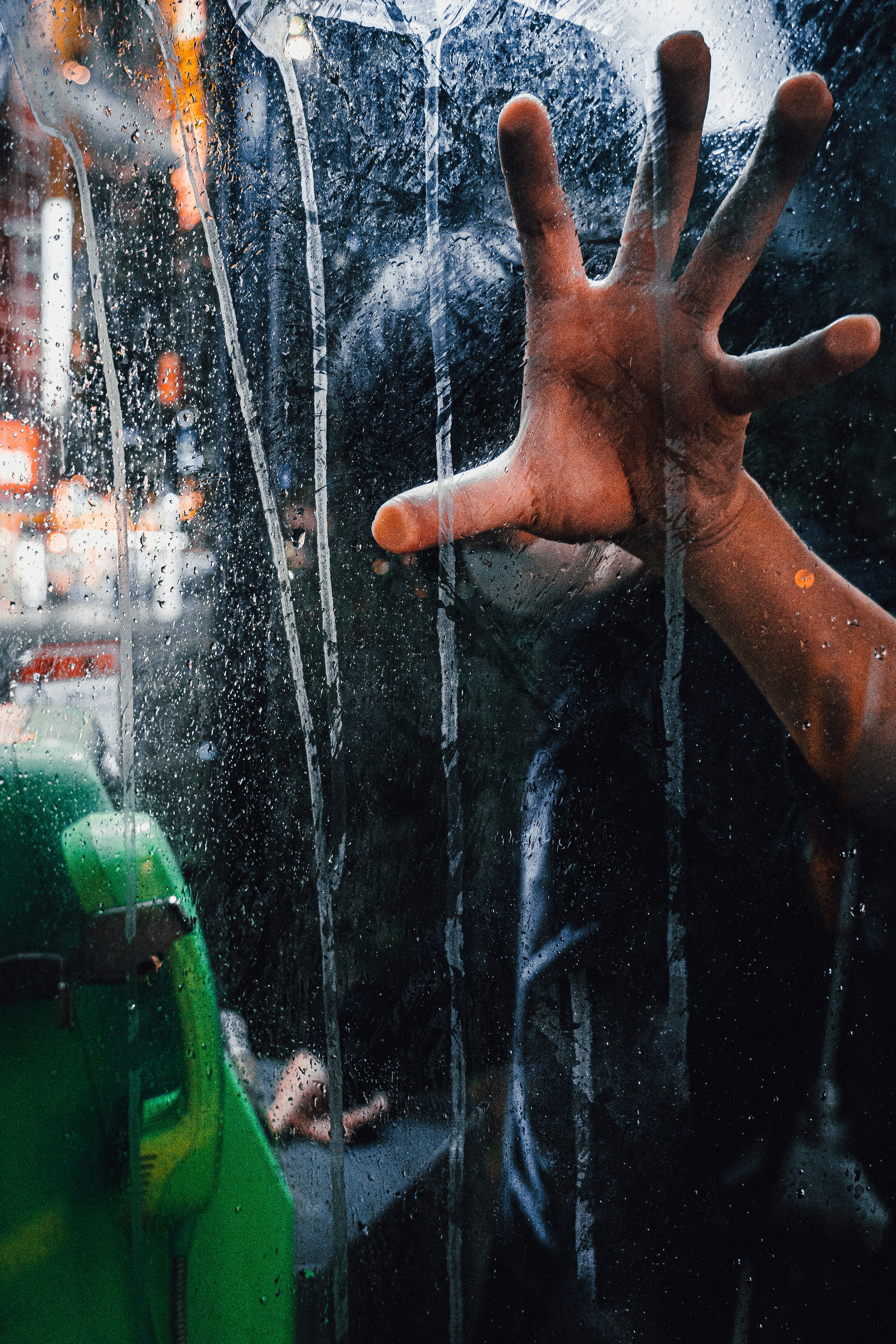 Silhouette of a person reaching out through fogged glass with a green object visible