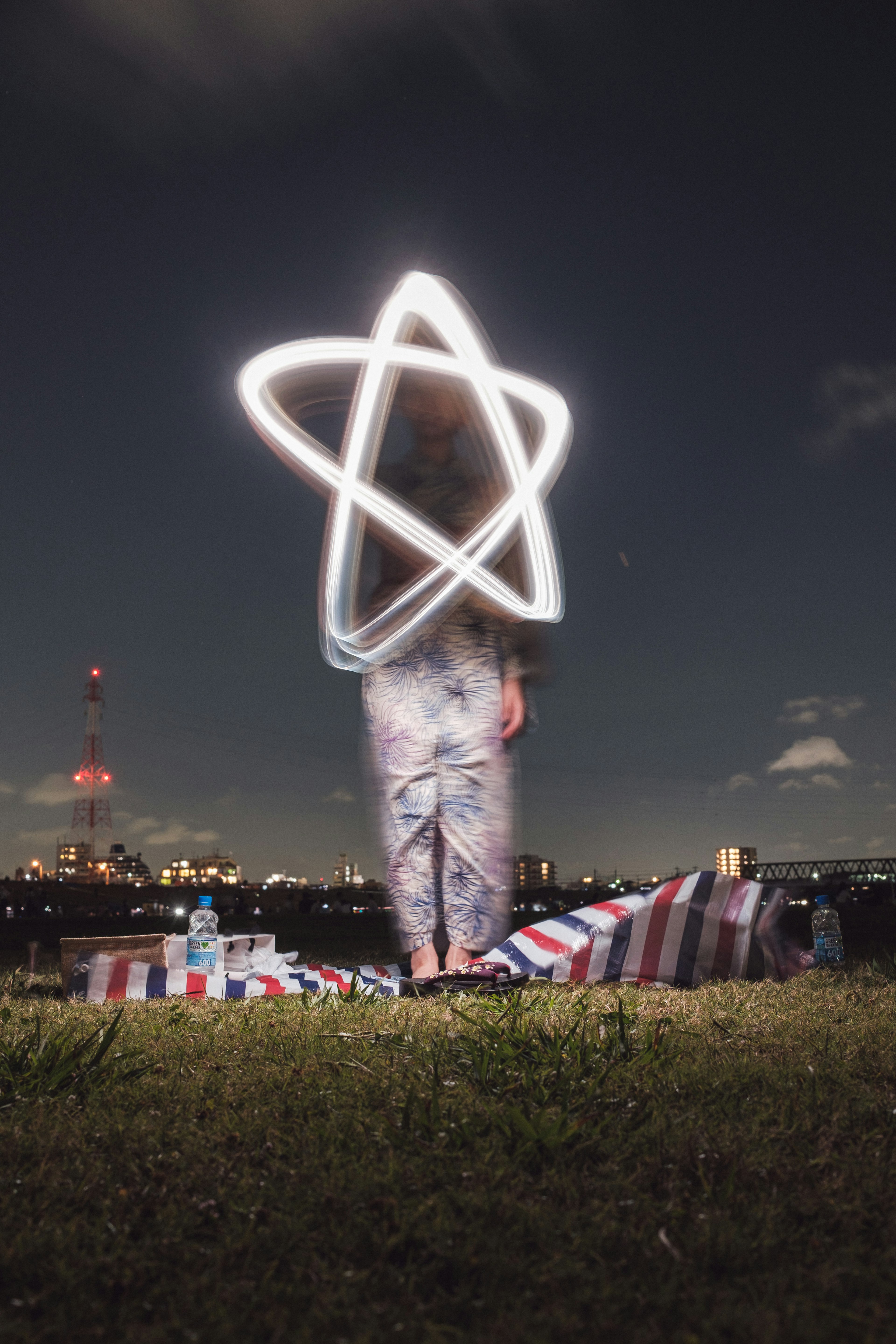 Silhouette of a person drawing a star with light under the night sky