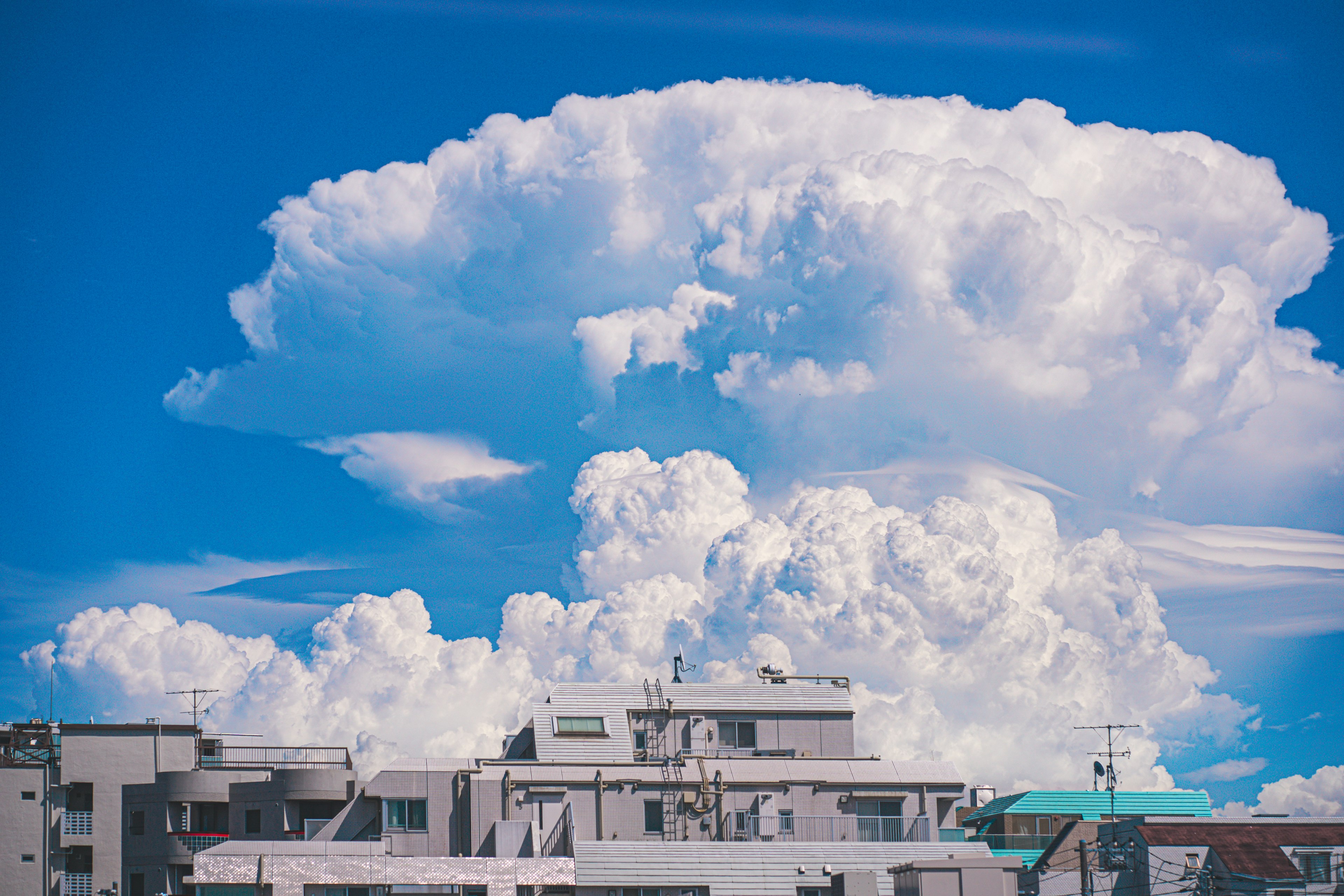 White clouds in a blue sky above a cityscape