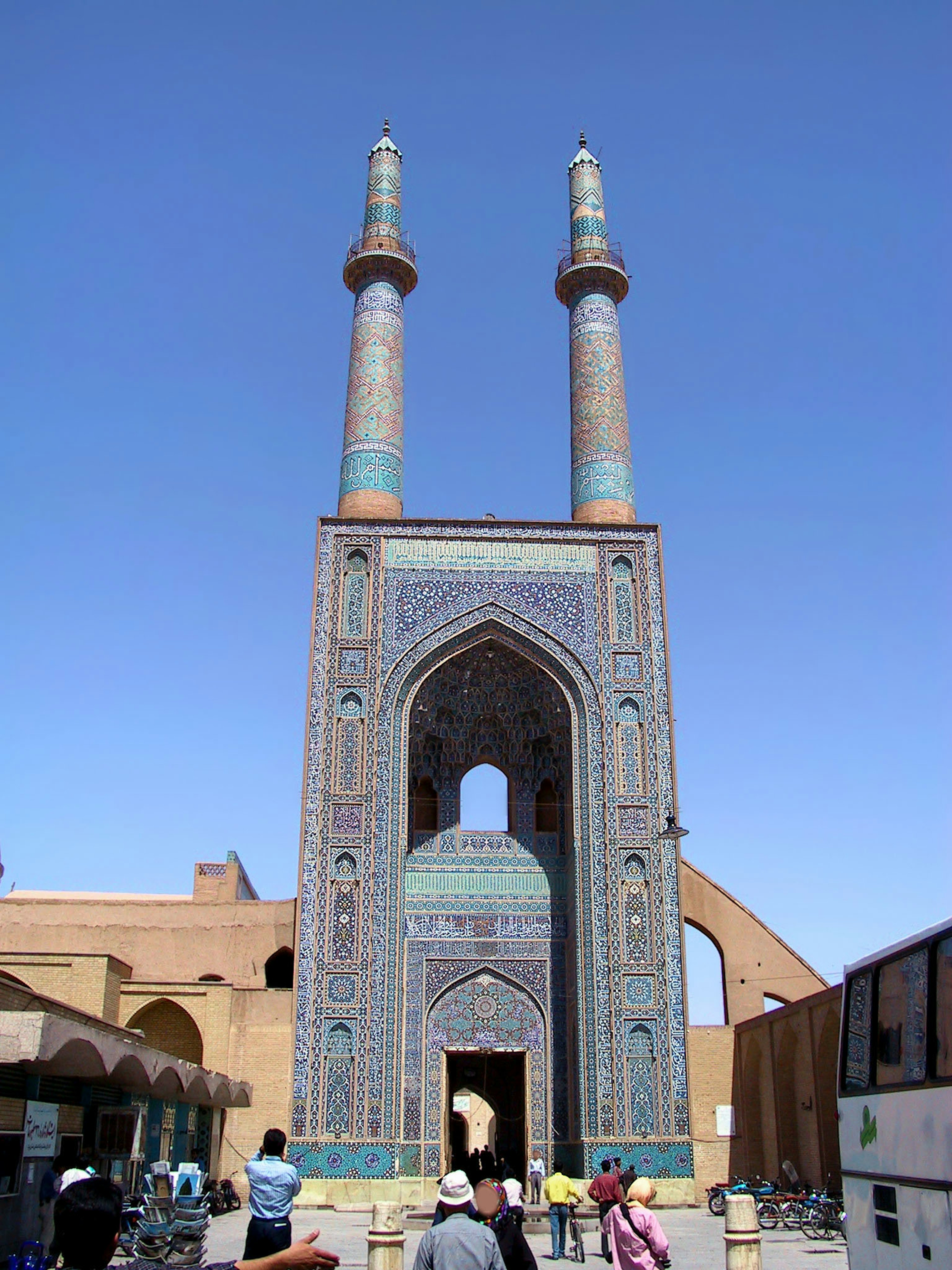 Entrance of a beautiful mosque in Yazd with two prominent minarets under a clear blue sky