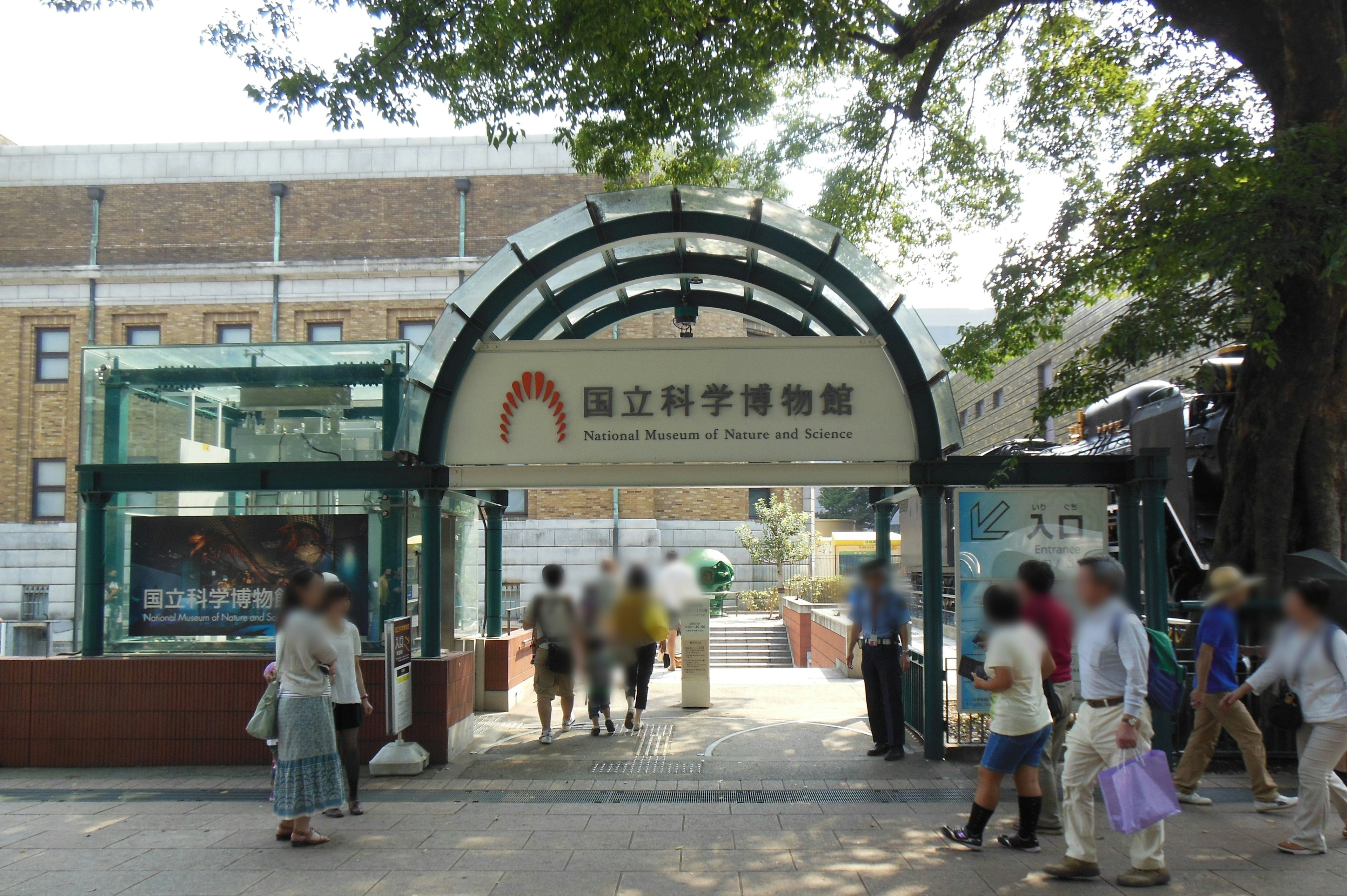 Entrance of a science museum with an arch sign and visitors