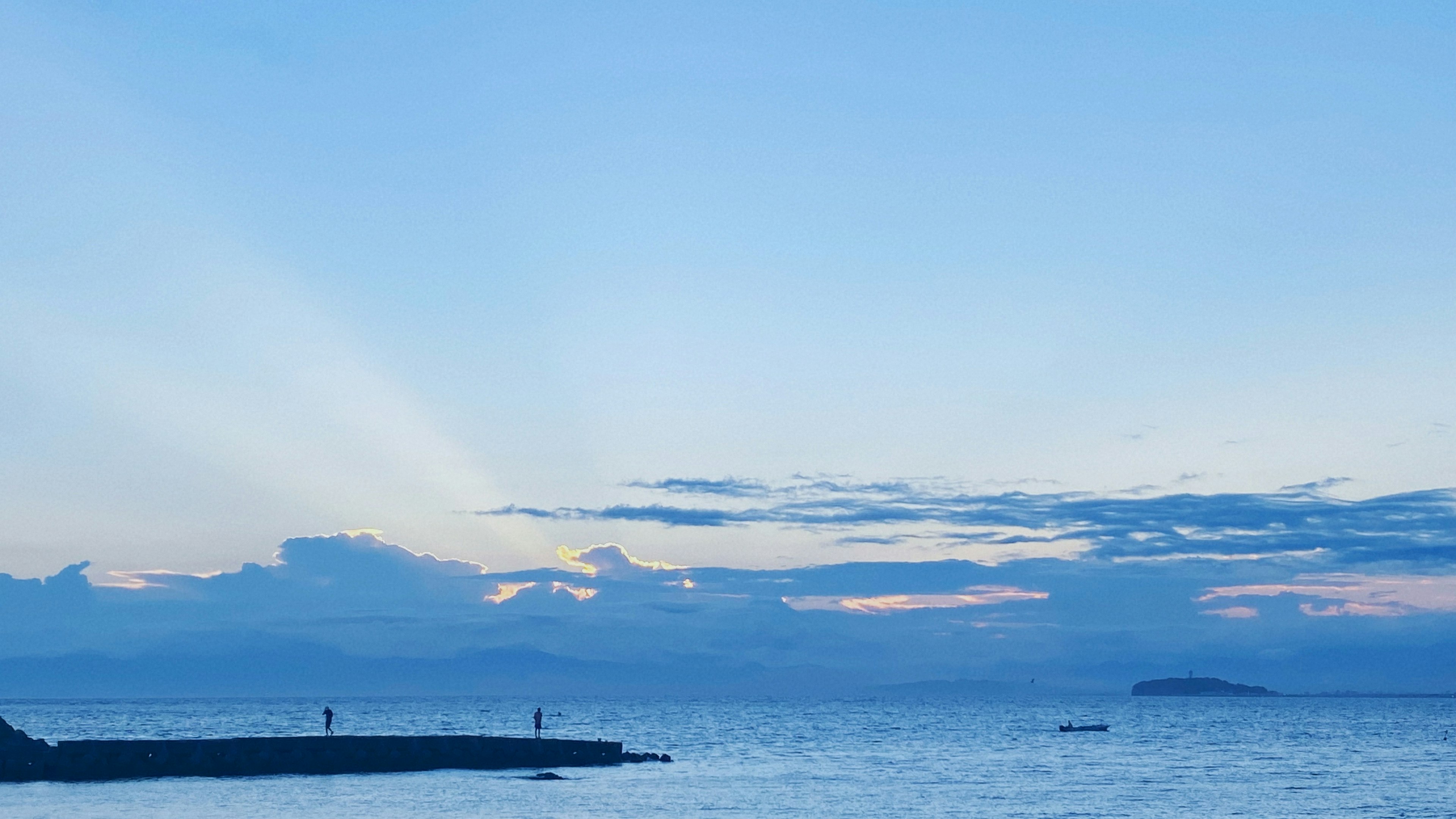 青い海と空の風景に人々が立っている