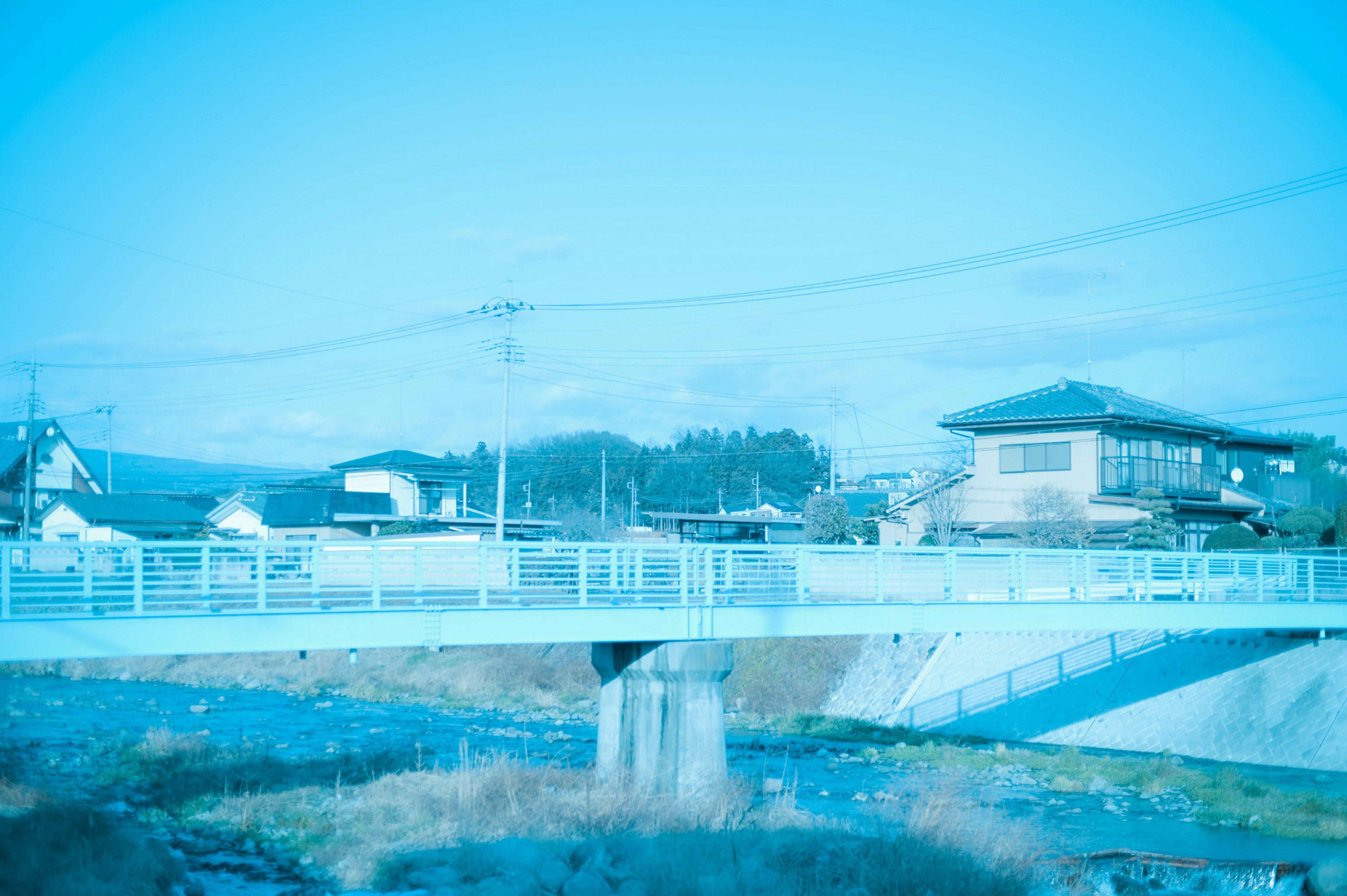 Una imagen azul de un puente y casas circundantes