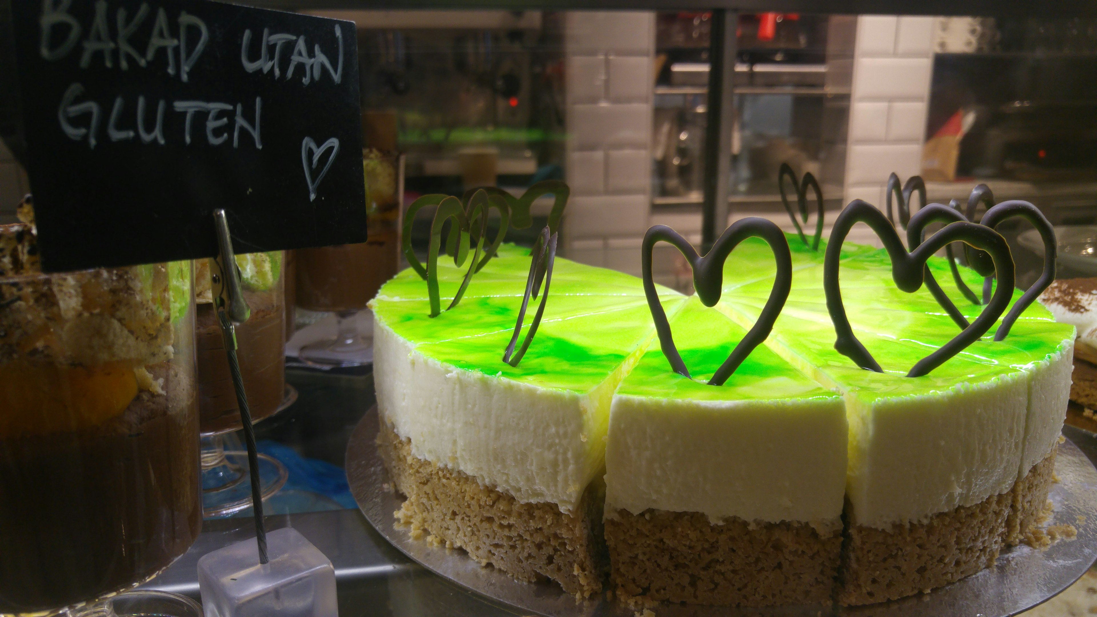 Layered cake with green jelly and cream topped with heart-shaped chocolate decorations