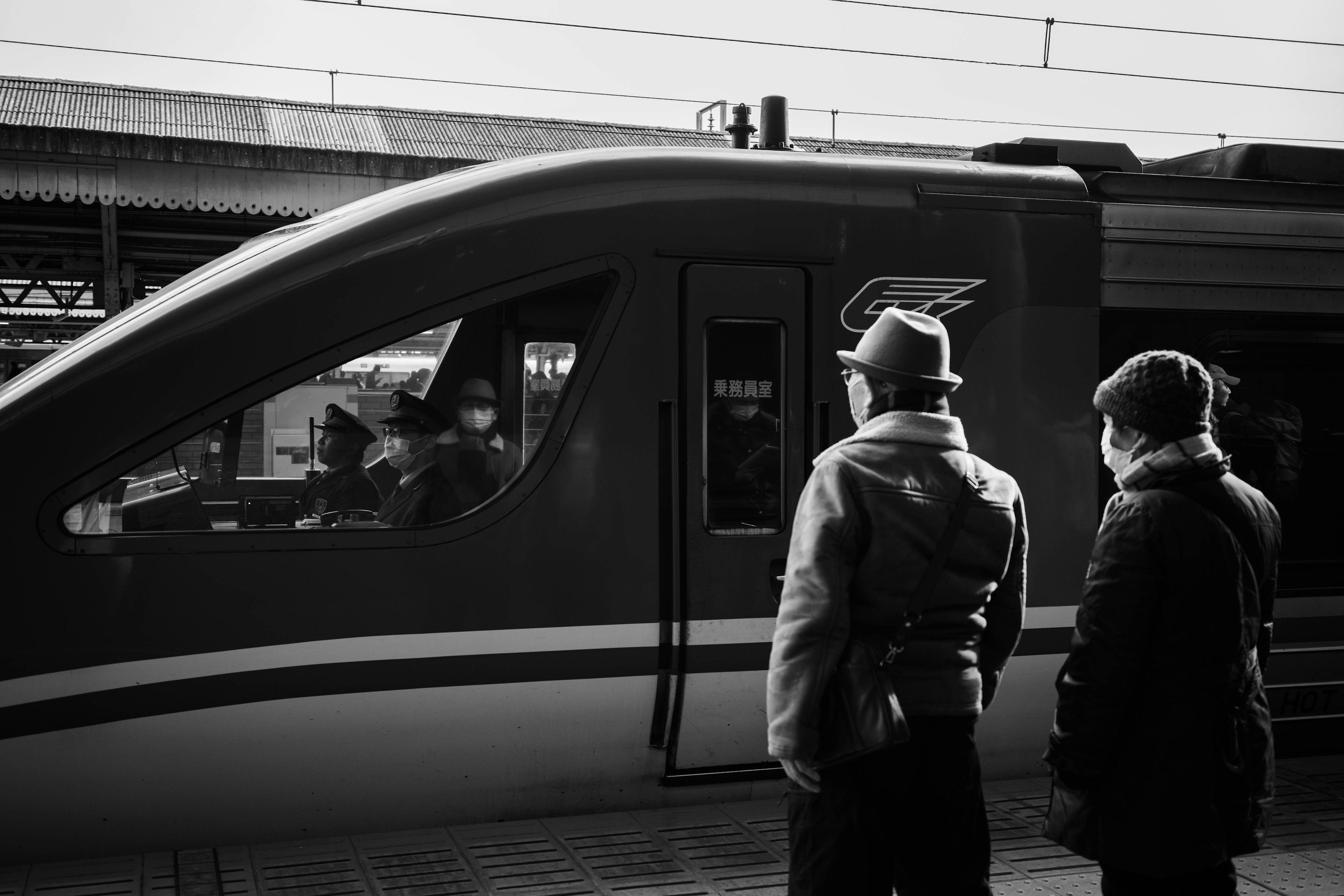 Schwarz-weiß Szene von zwei Personen, die einen Zug an einem Bahnhof beobachten