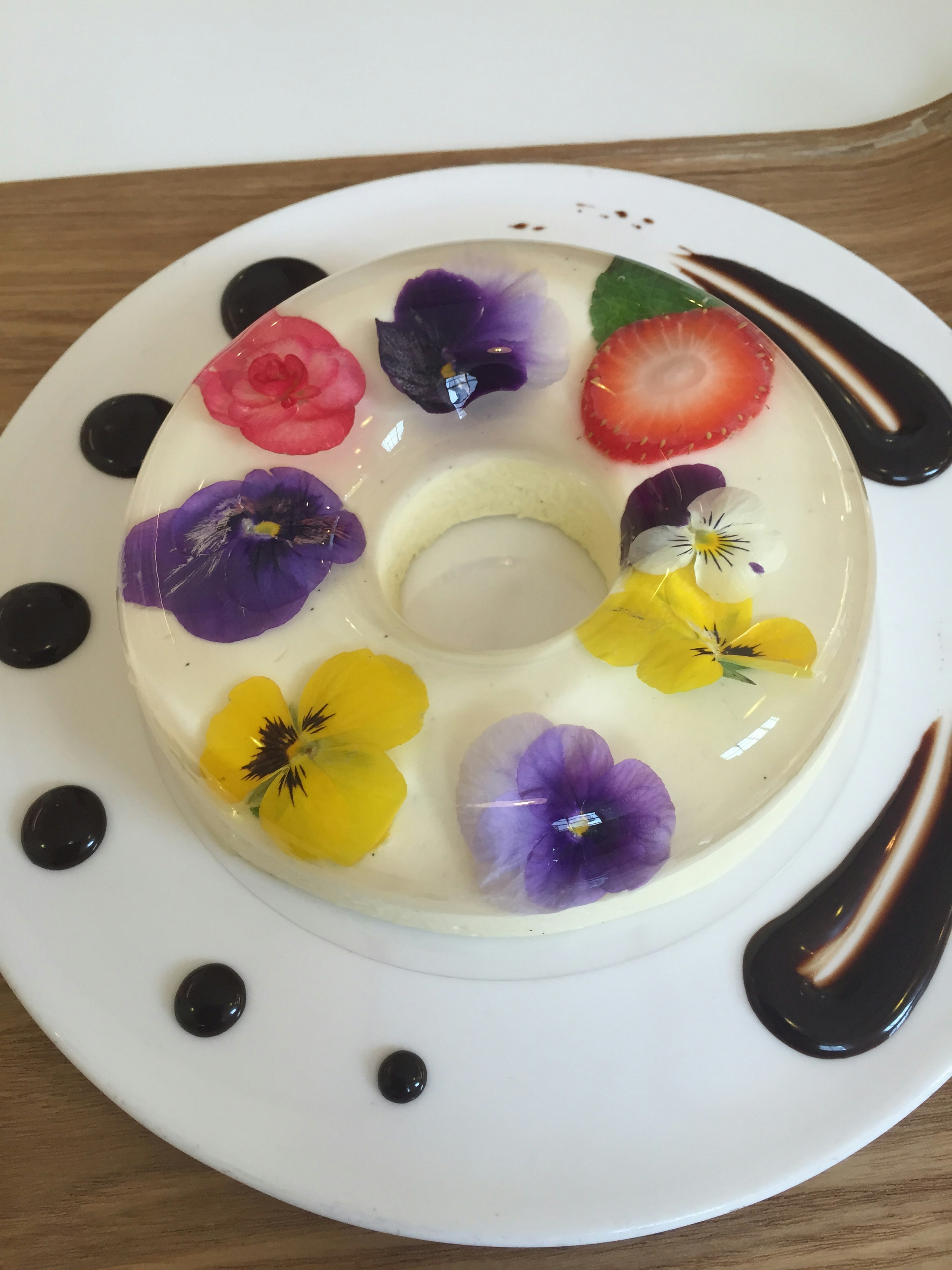 Dessert topped with colorful edible flowers and strawberries