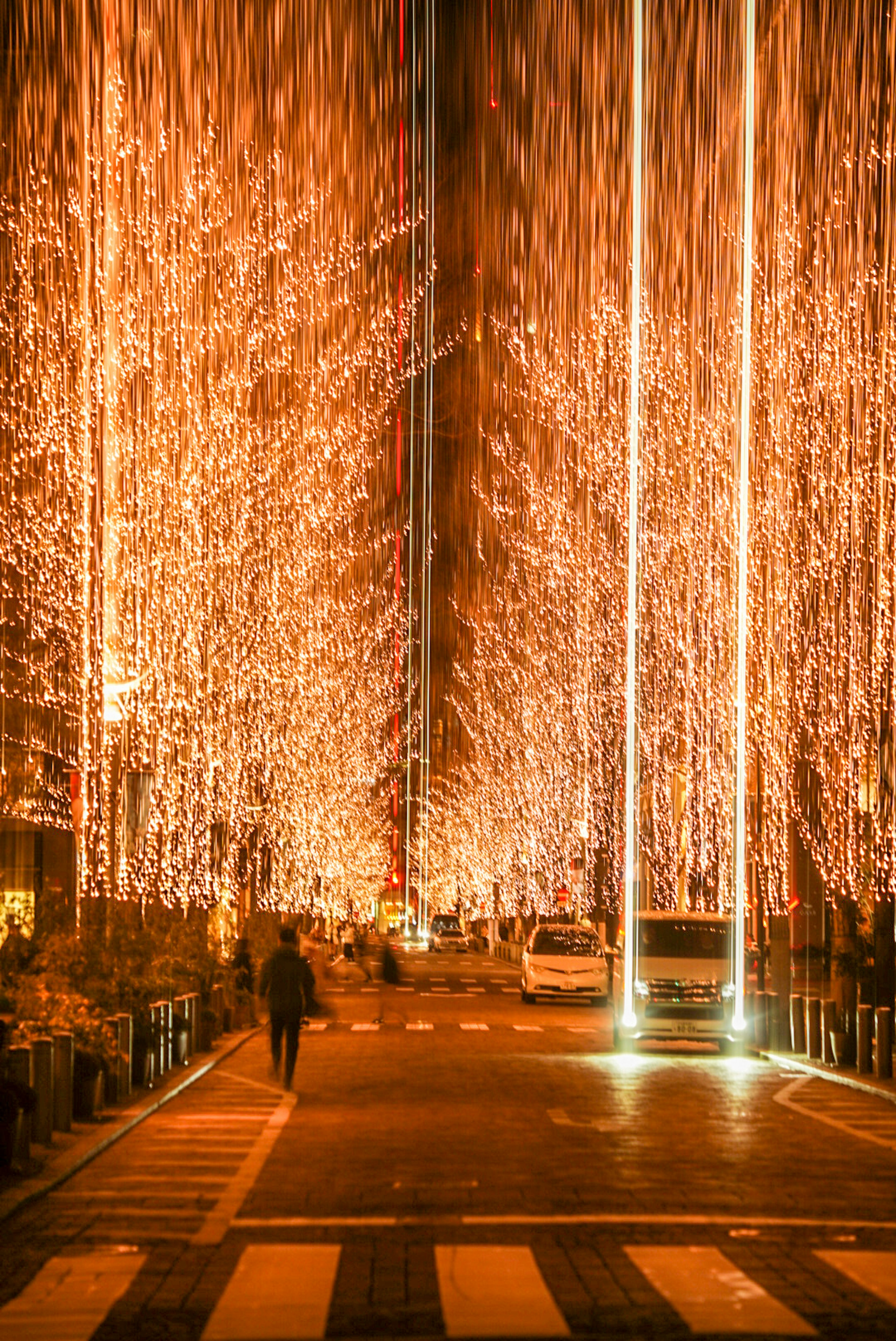 Calle bordeada de luces brillantes y un peatón