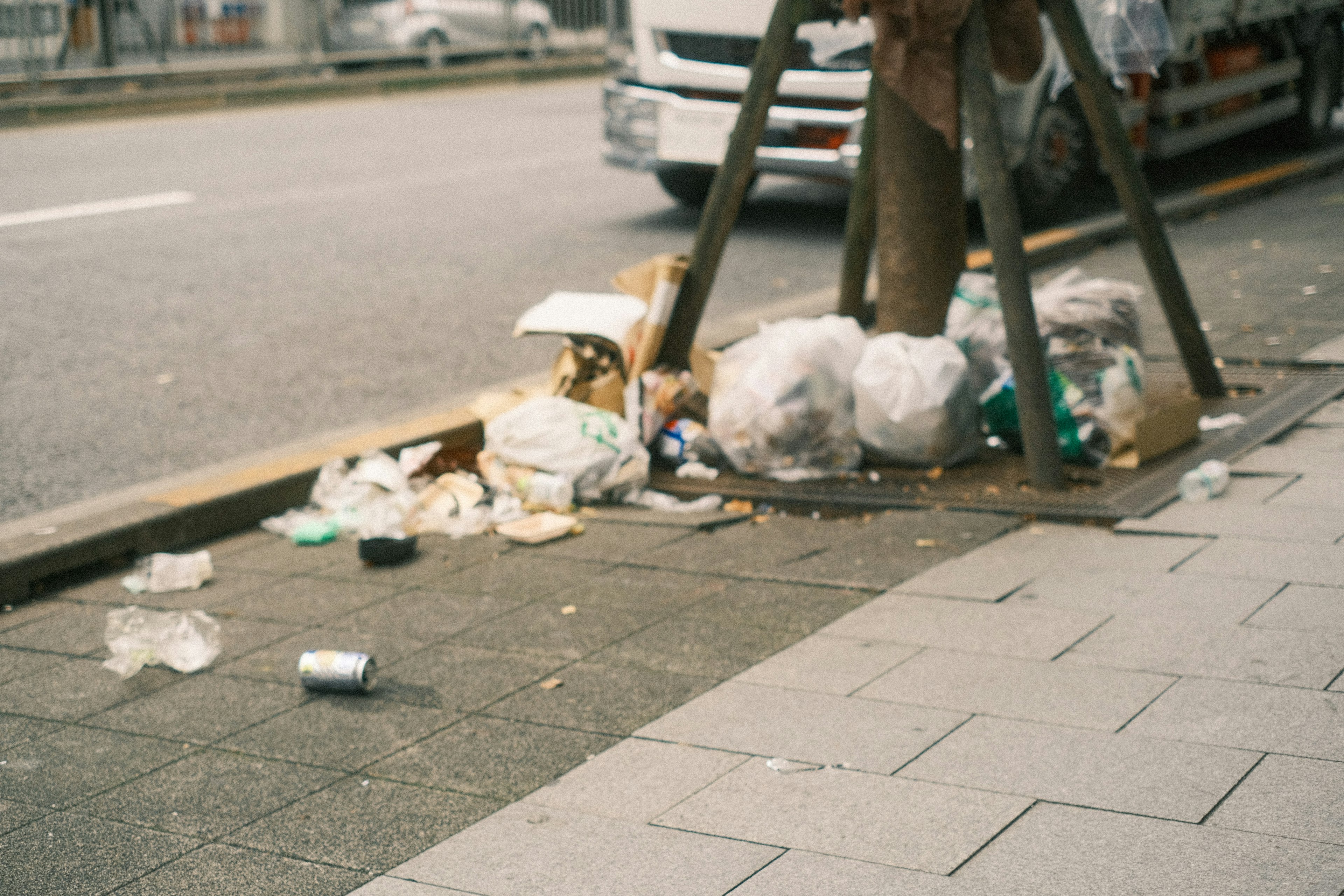 A pile of litter and trash bags on a city sidewalk