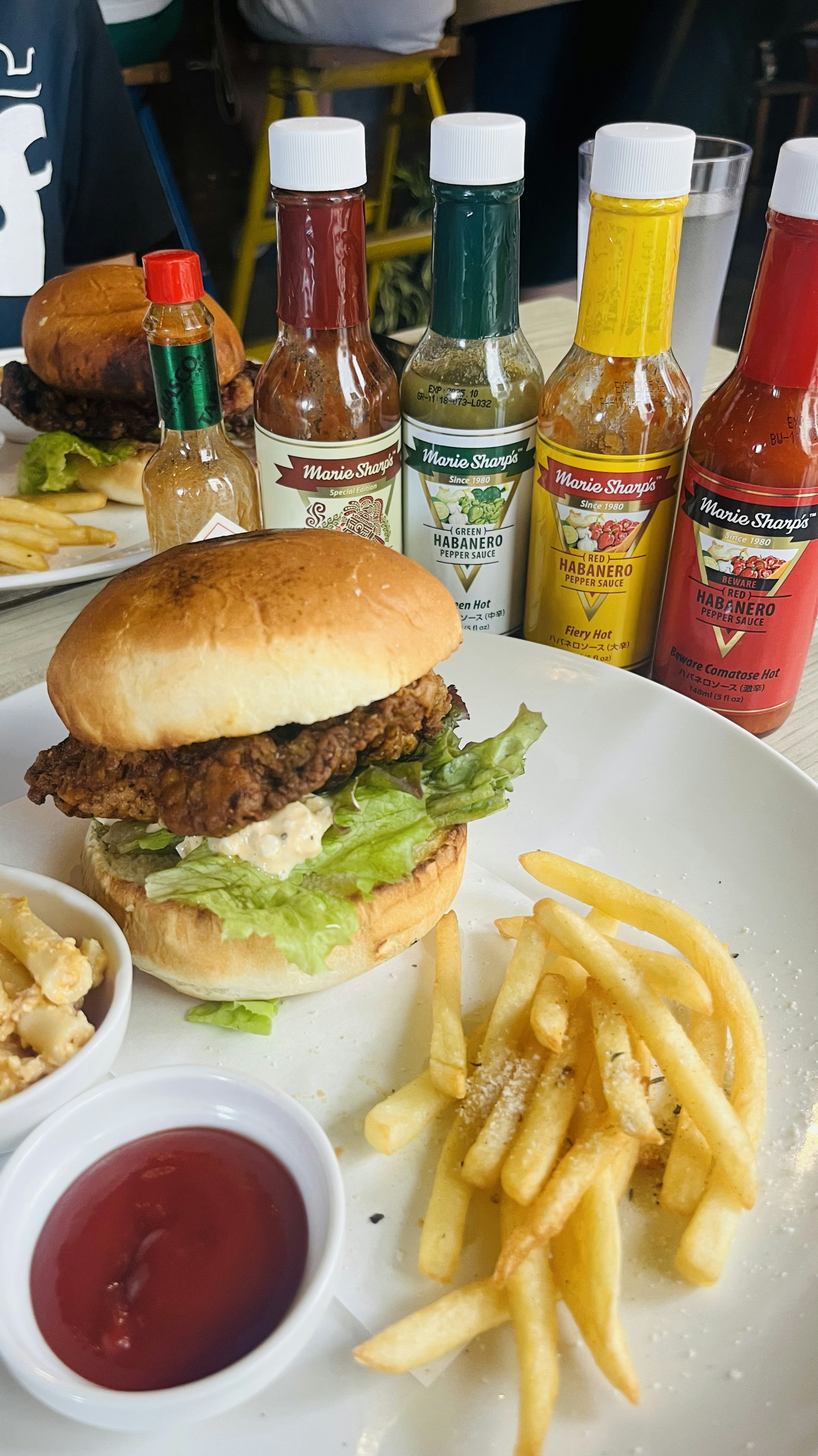 Ein Teller mit einem Hamburger mit Salat und Pommes frites sowie verschiedenen scharfen Saucen