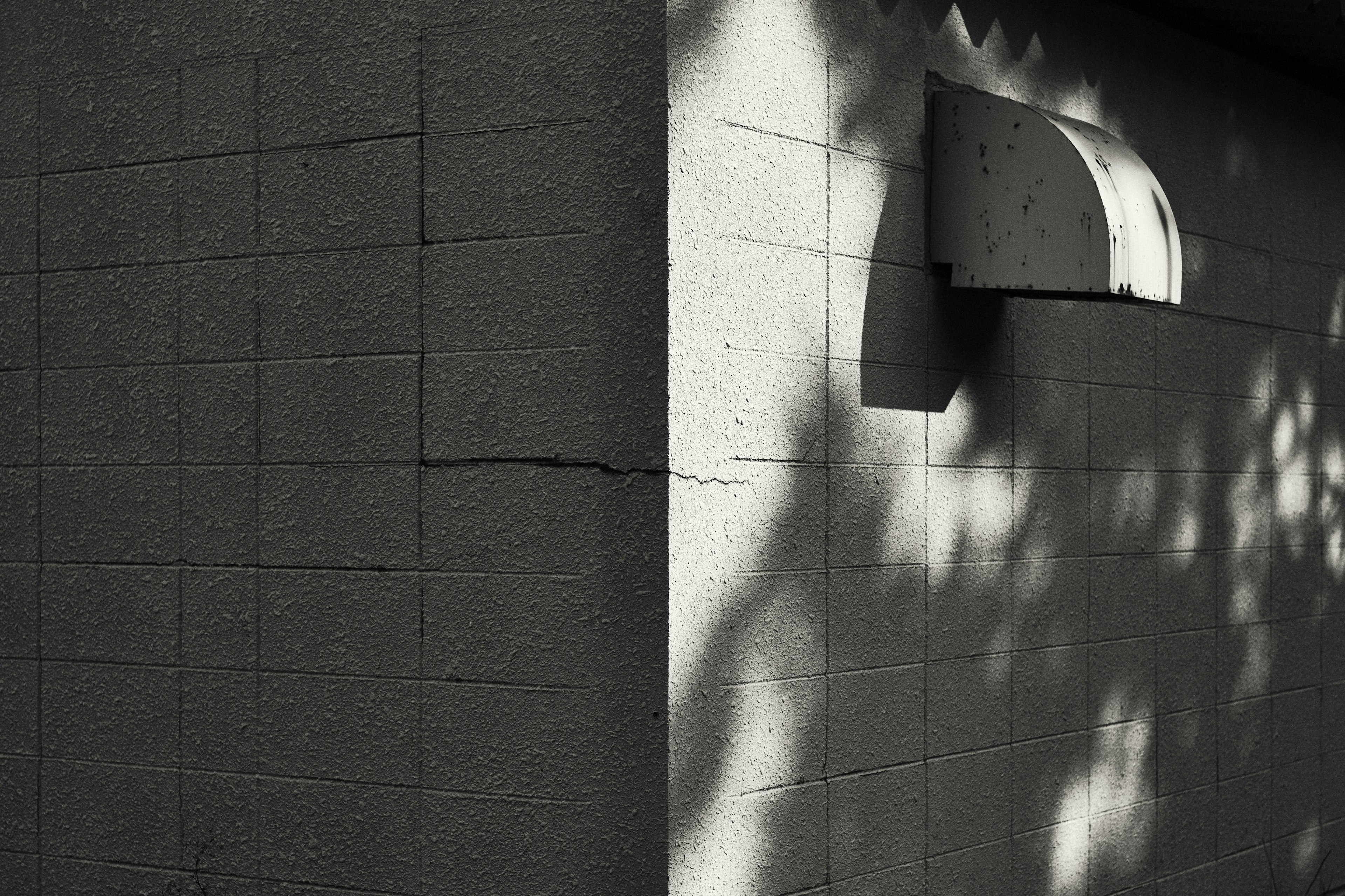 Coin d'un mur noir texturé avec des ombres et un petit rebord