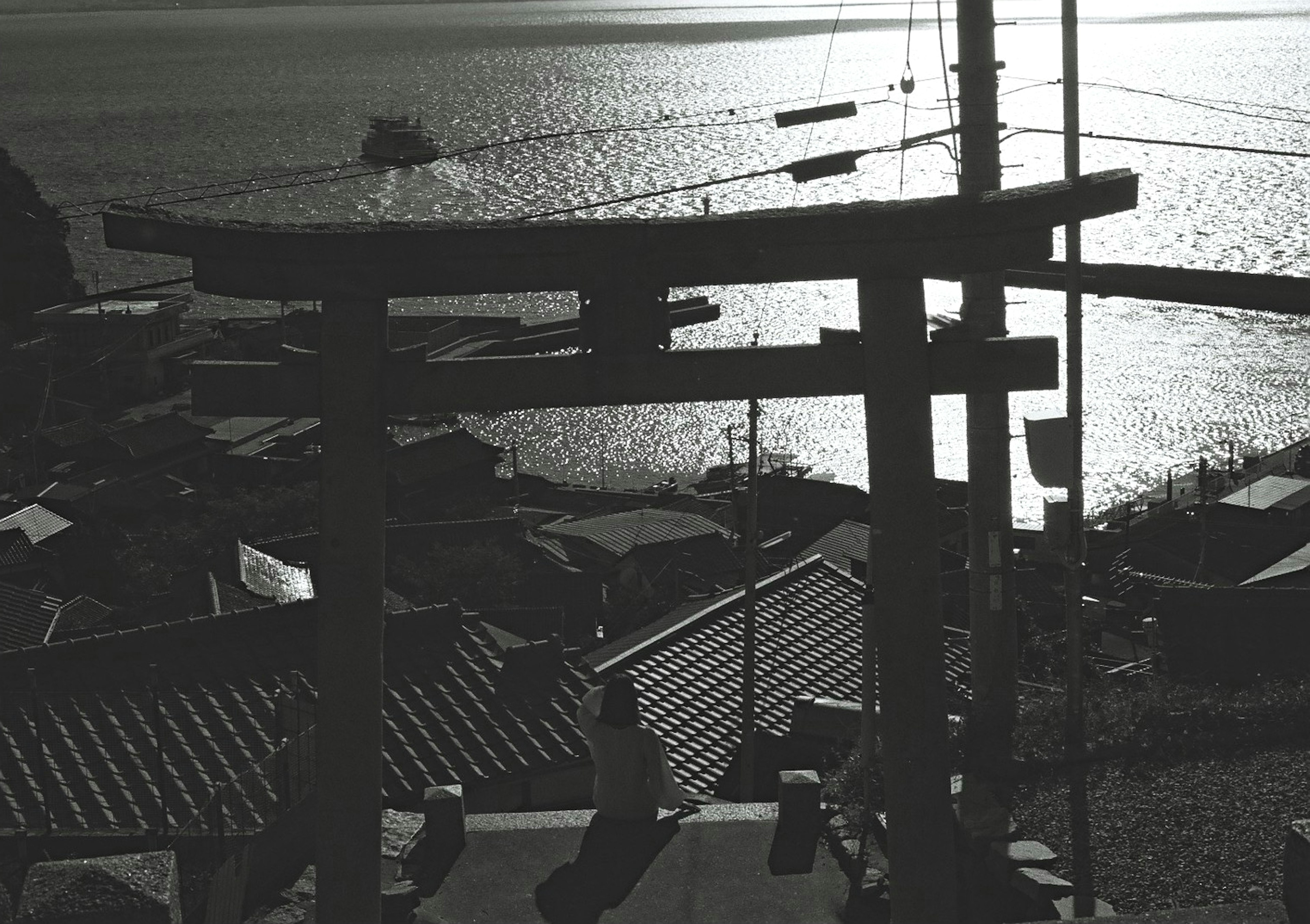 Silueta de una puerta torii con vista al mar y barcos pesqueros