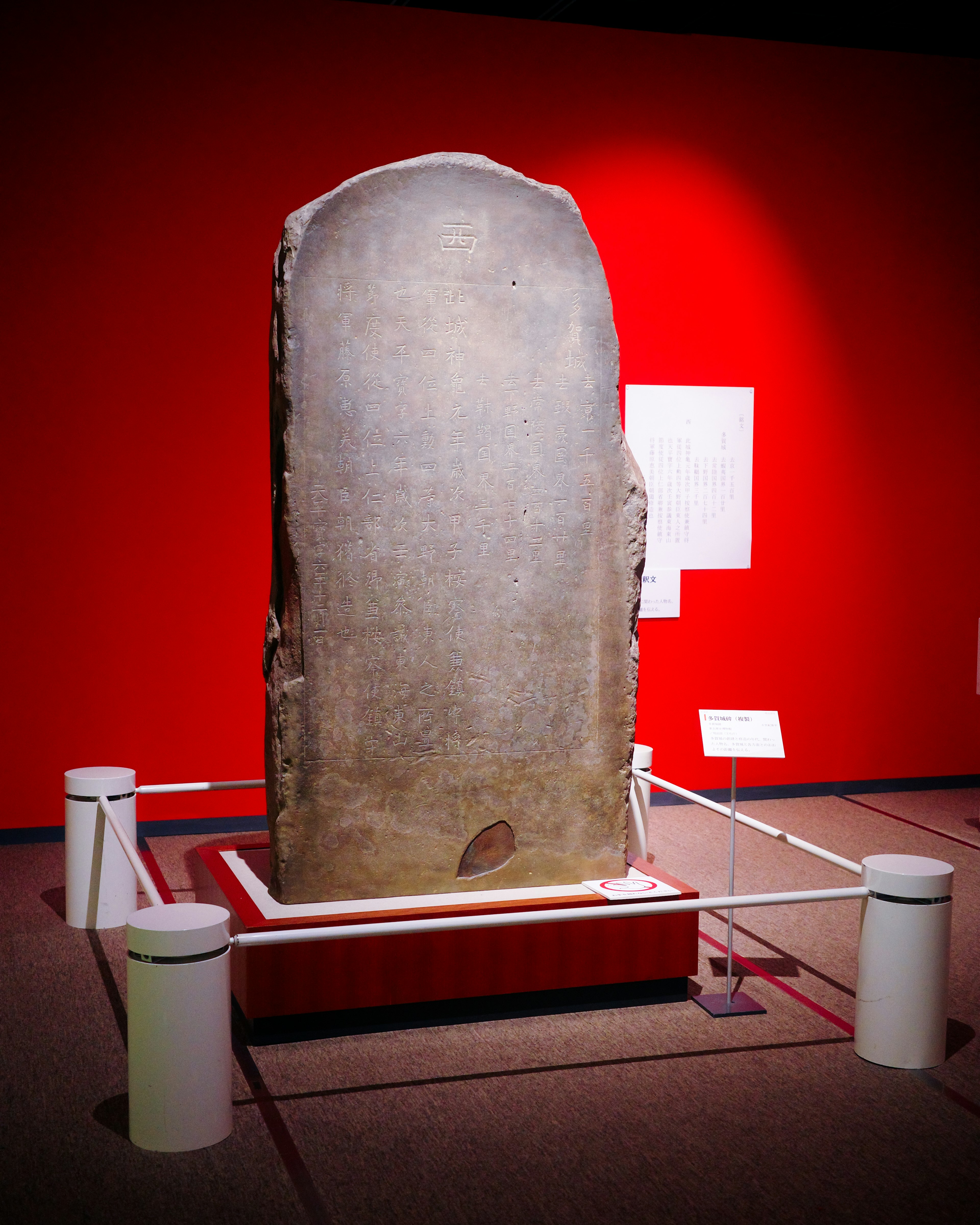 Große Steintafel in einer Museumsausstellung mit rotem Hintergrund