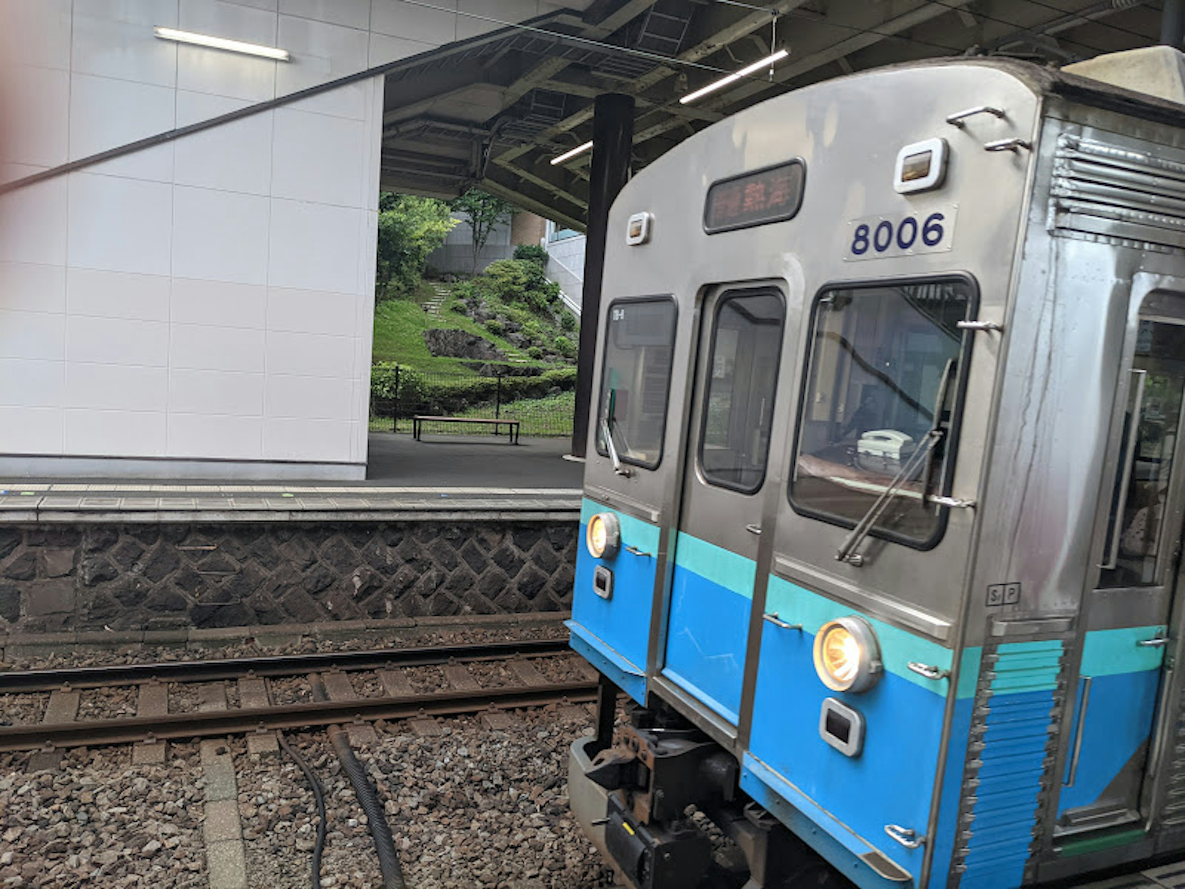 青いラインのある銀色の電車が駅に停車中