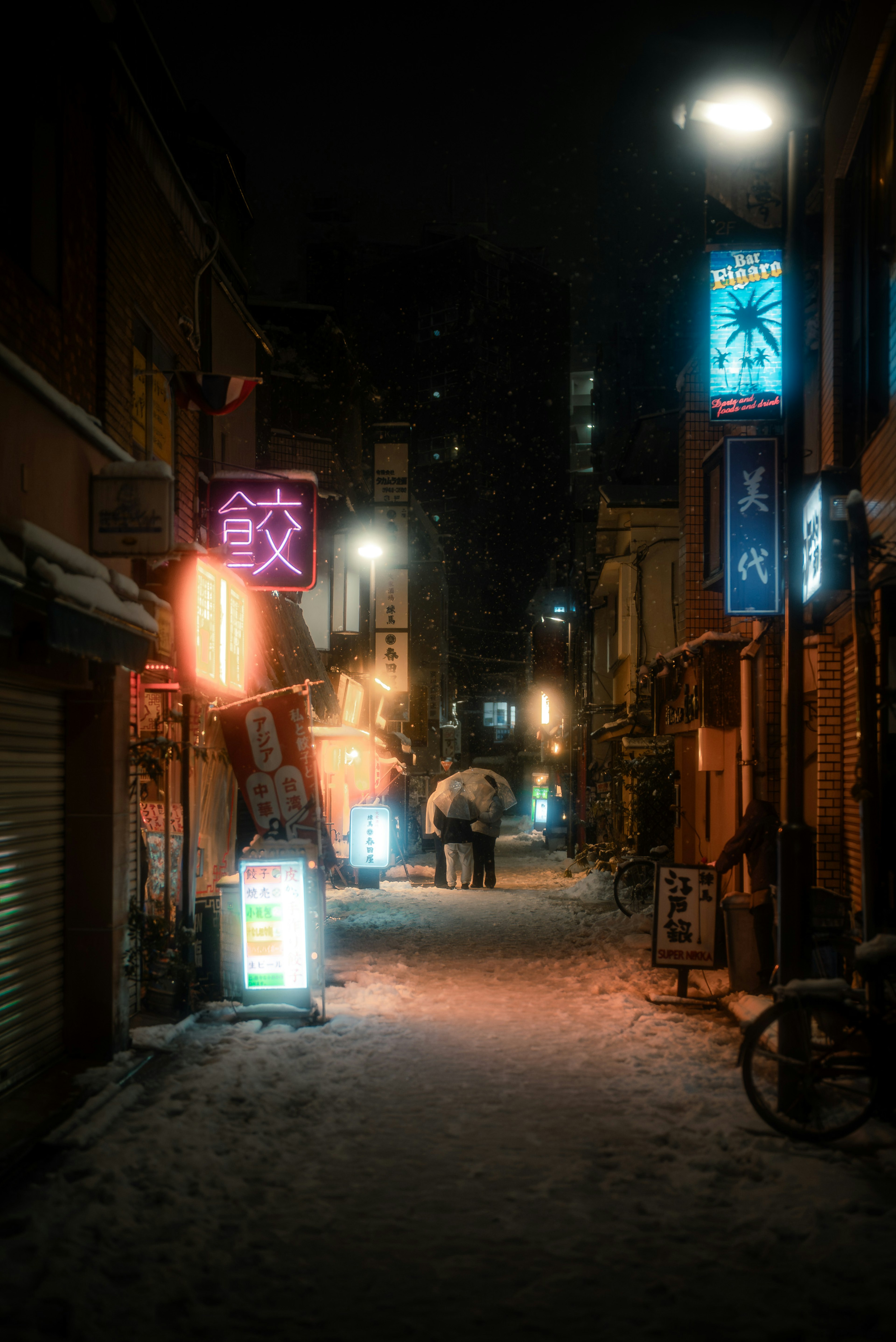 Callejón estrecho de noche con letreros de neón brillantes y nieve