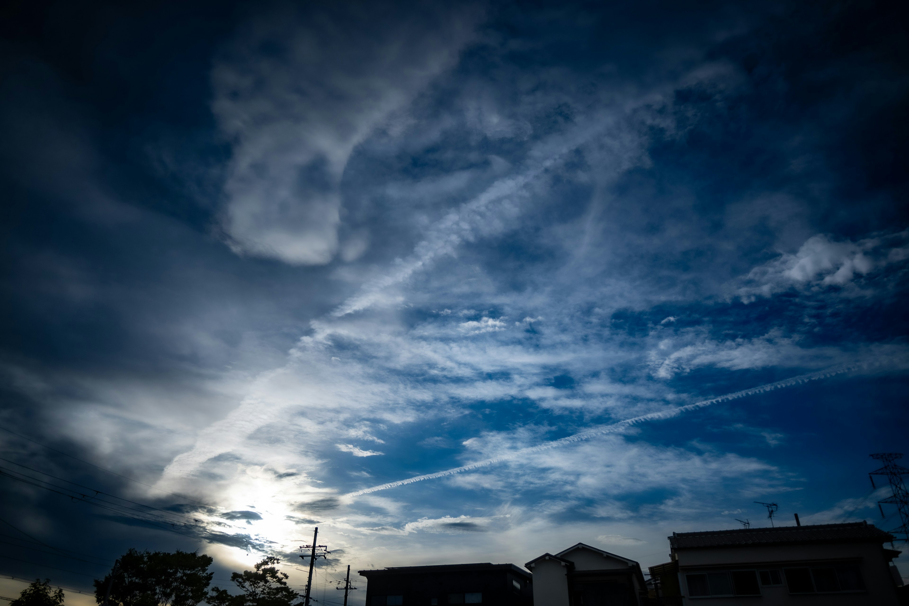 Un paysage avec un ciel bleu rempli de nuages et un soleil visible