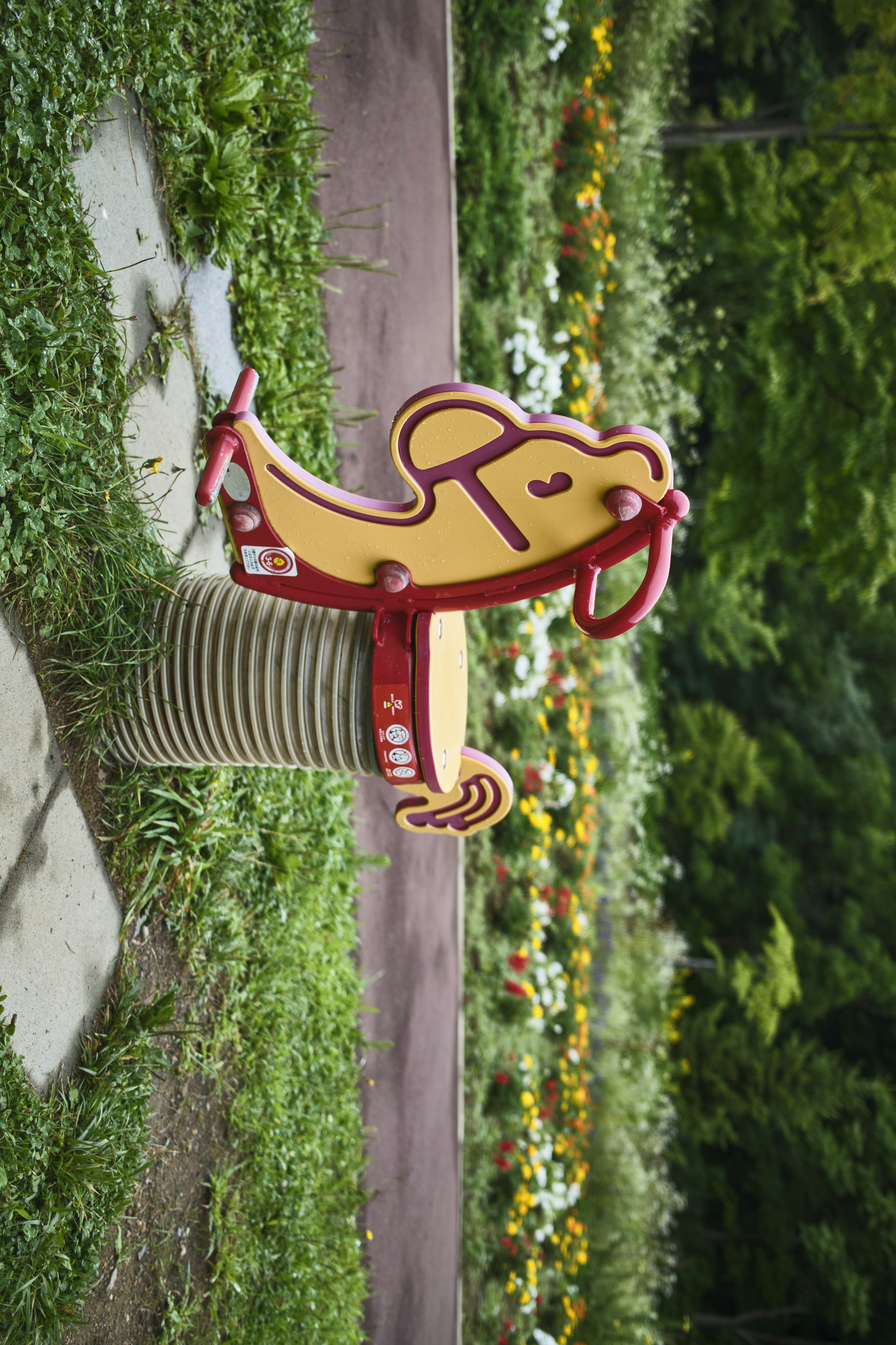 Colorful fish-shaped playground equipment surrounded by blooming flowers