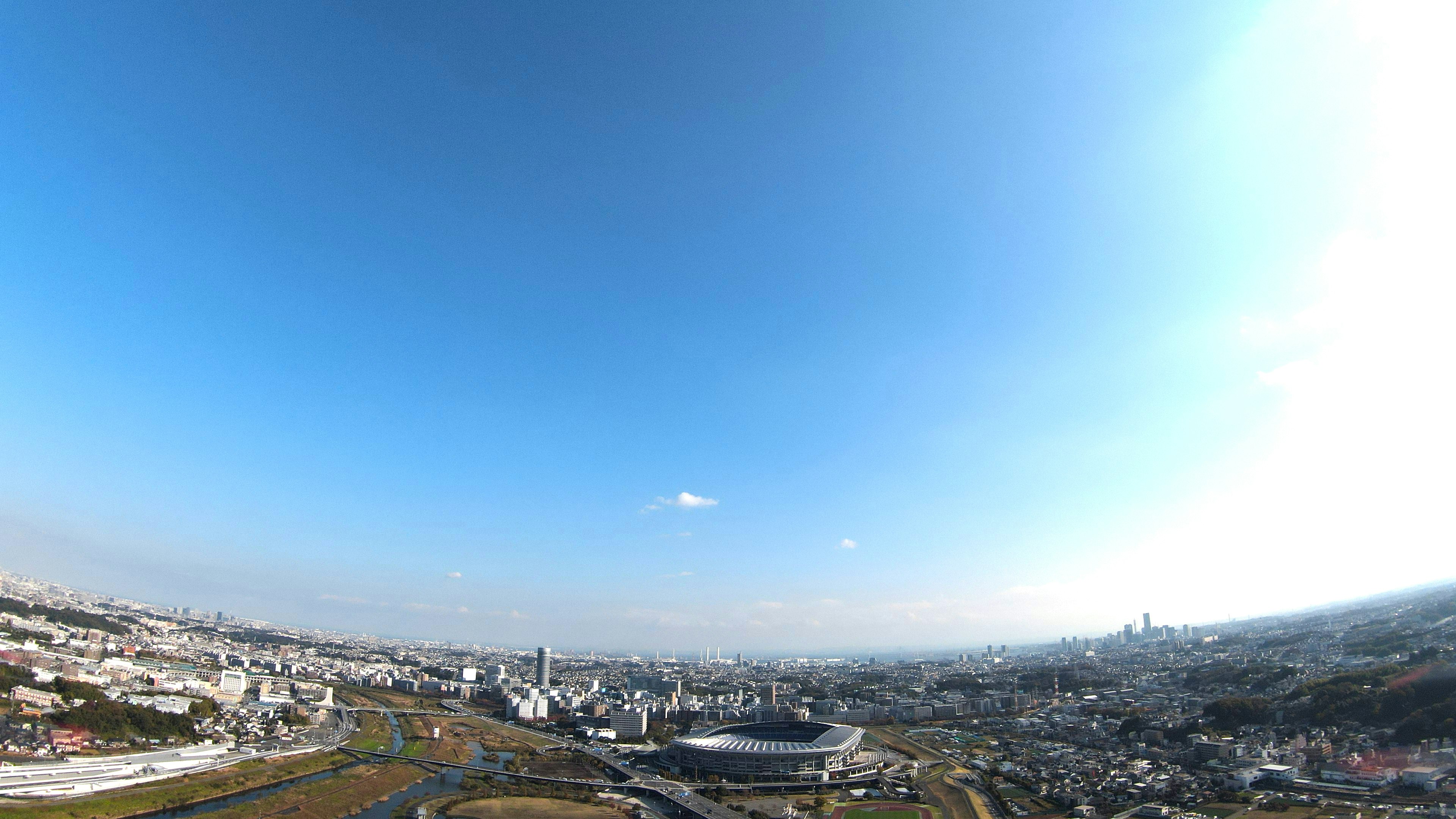 Pemandangan panorama kota di bawah langit biru cerah dengan stadion dan gedung pencakar langit terlihat