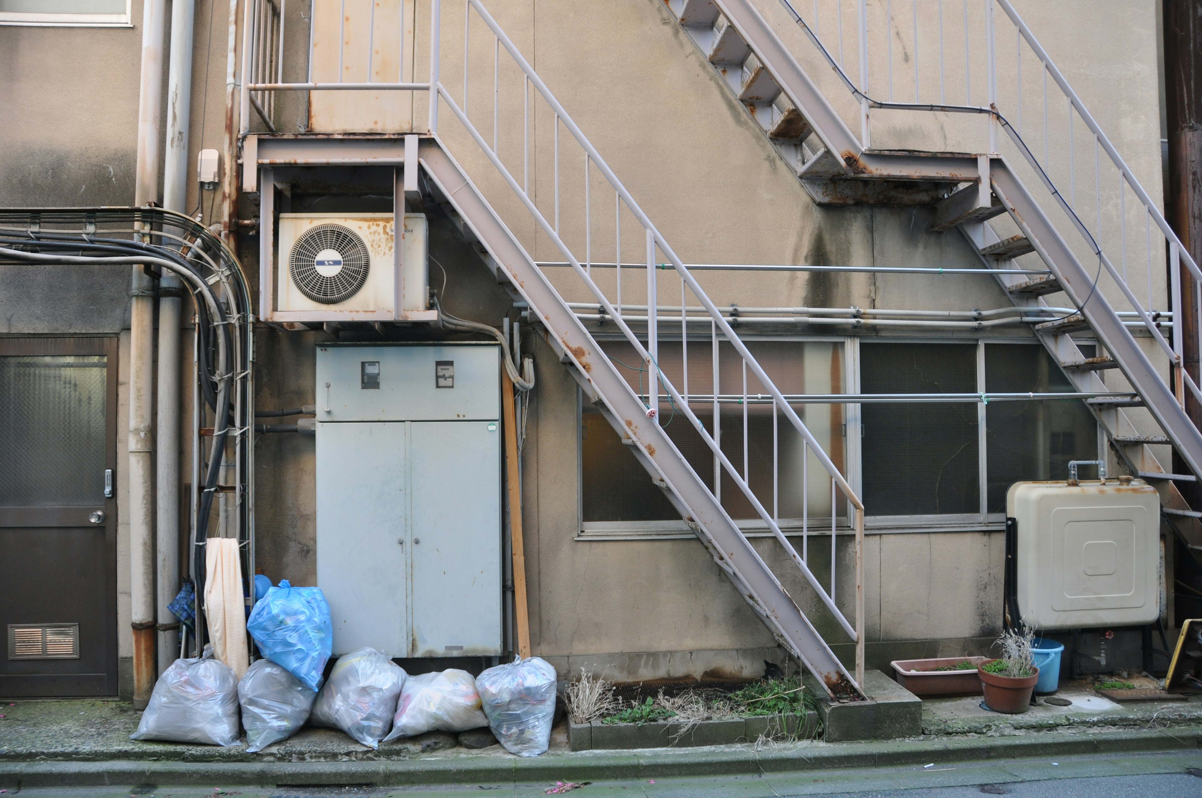 Vista exterior de un edificio con una escalera y una unidad de aire acondicionado