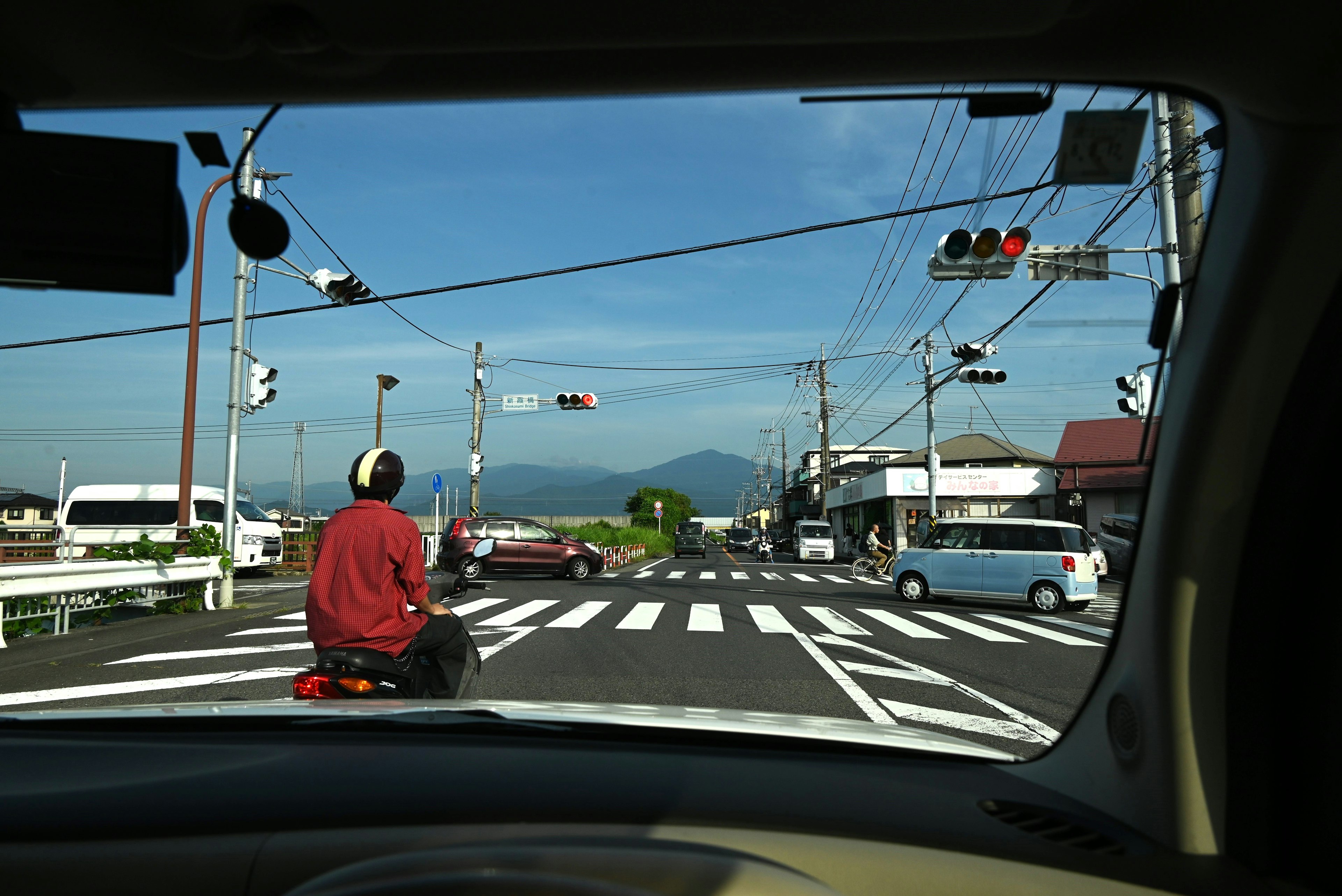 從車窗外看，顯示交通信號和人行道，背景有一座山