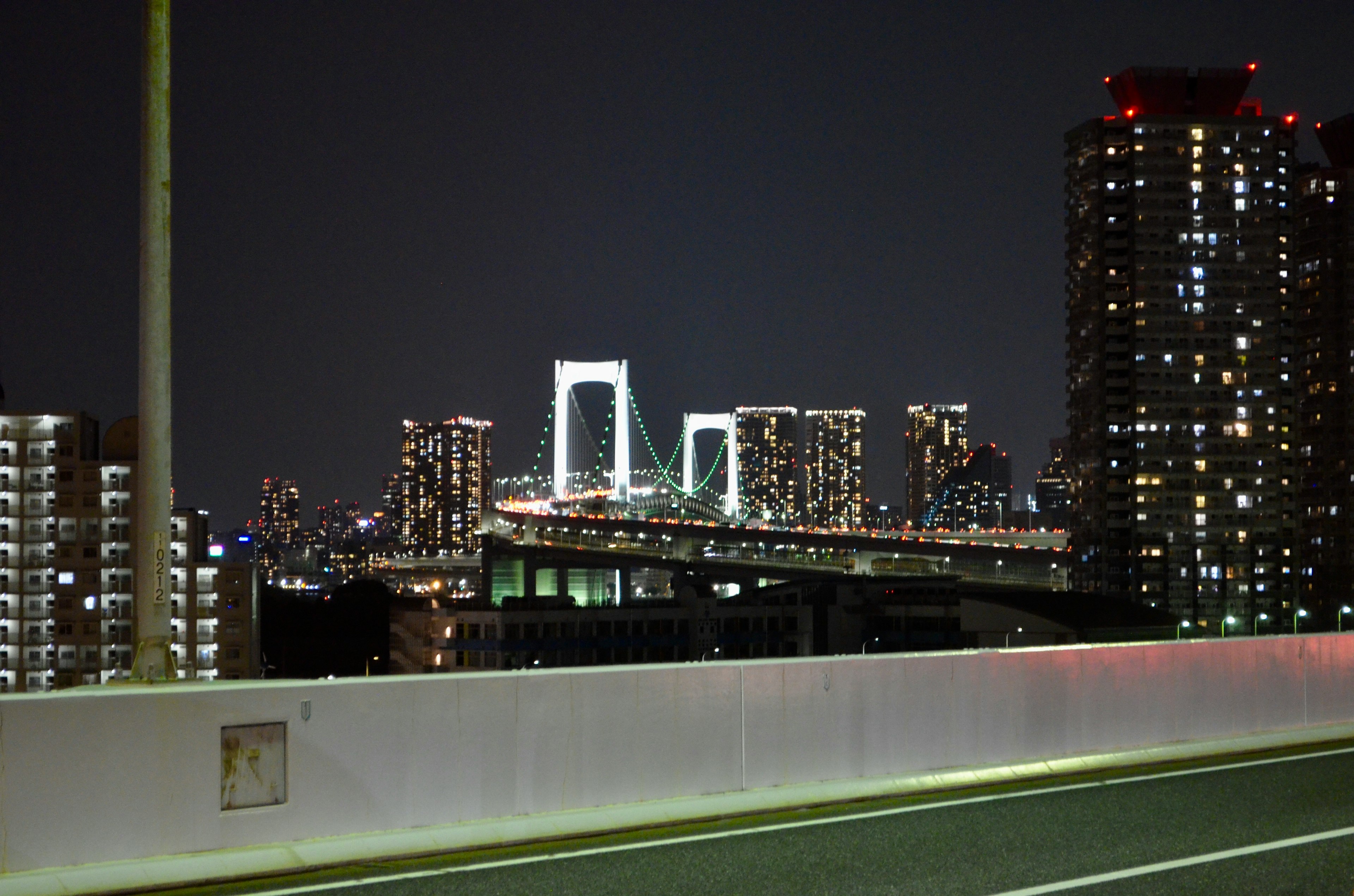 Vista nocturna del puente Rainbow y rascacielos