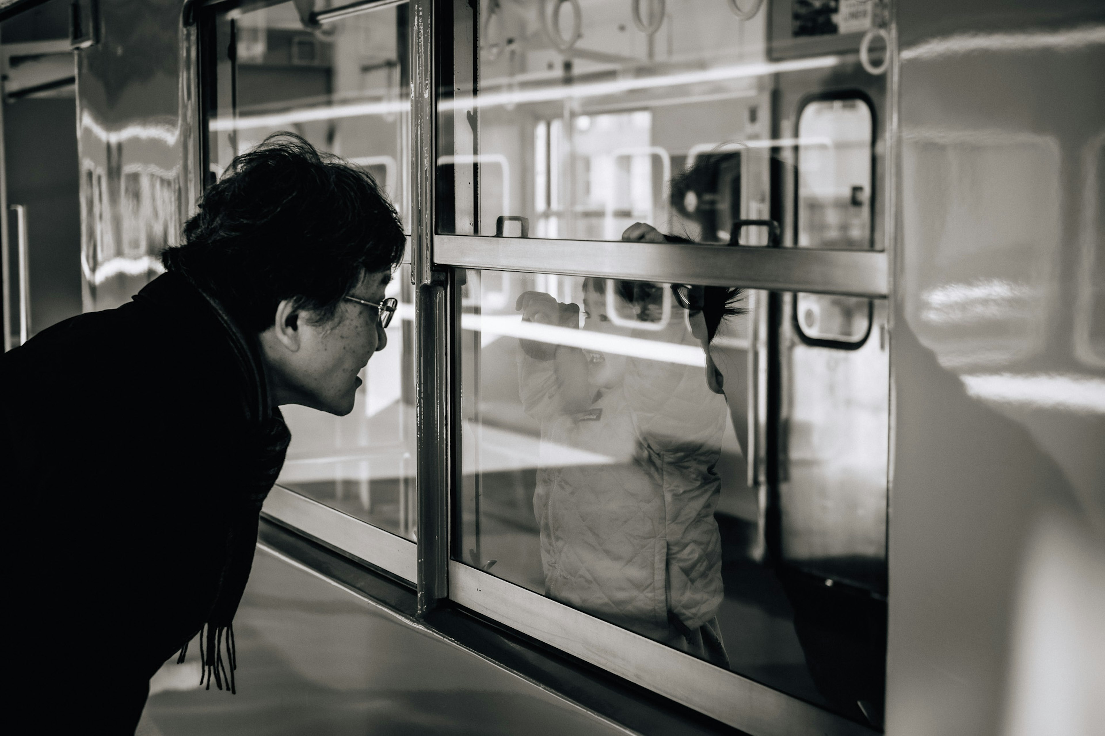 A person peering through a window in a black and white photo