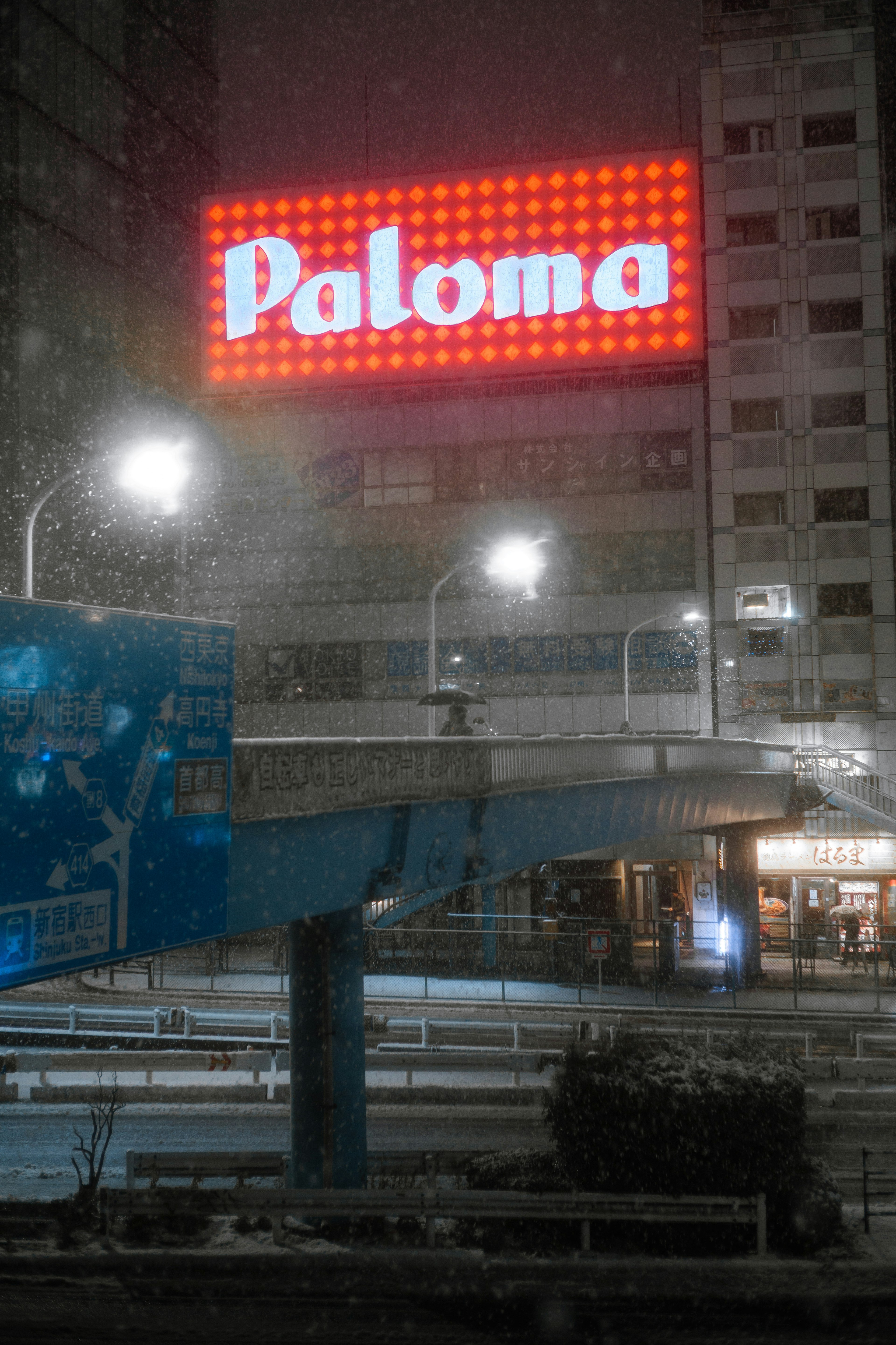 Helles Paloma-Schild im Schnee mit dunklem Stadt Hintergrund