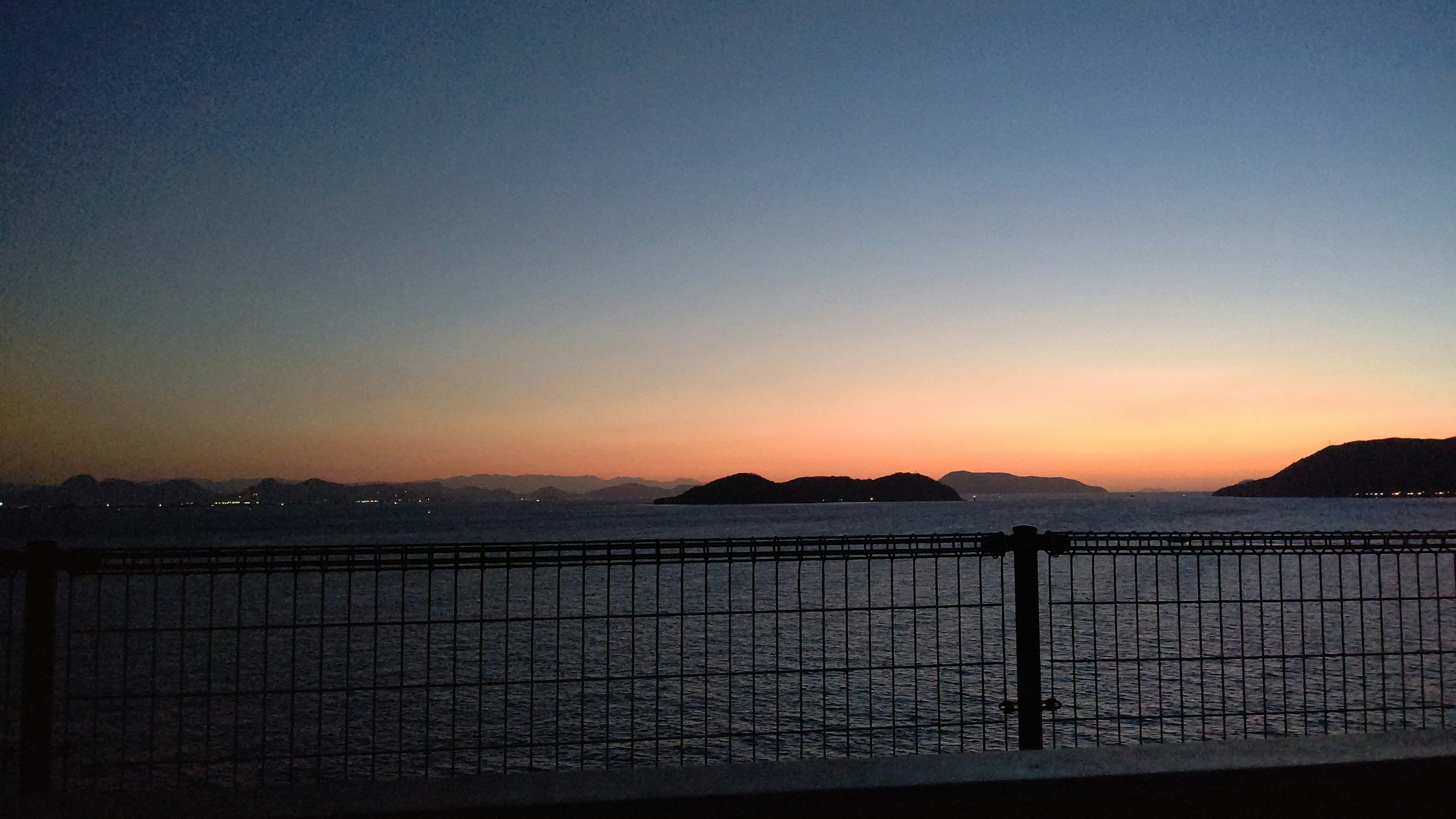 Pemandangan indah langit senja di atas laut dengan pulau-pulau jauh