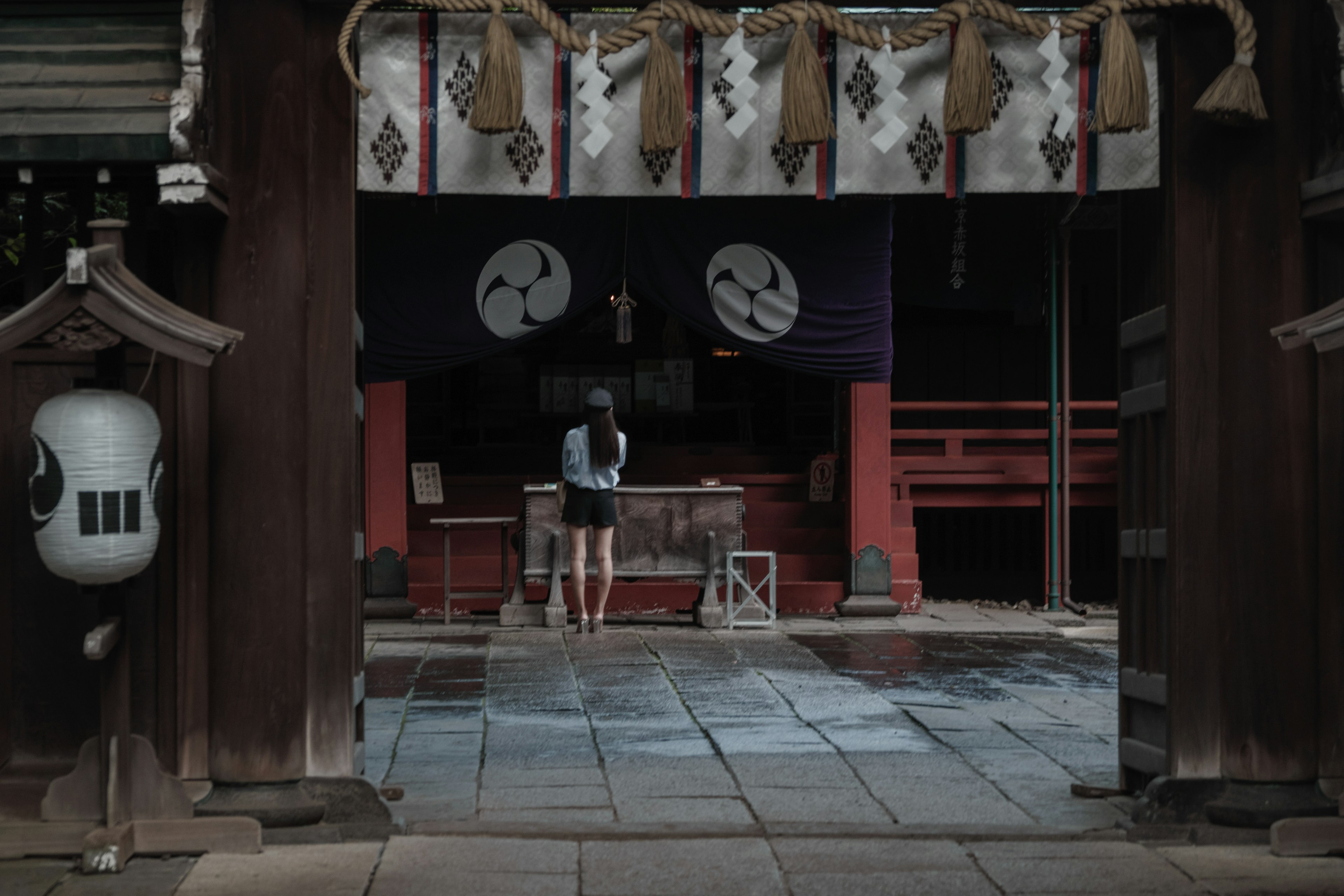 A woman standing inside a shrine with traditional decorations and a red torii gate