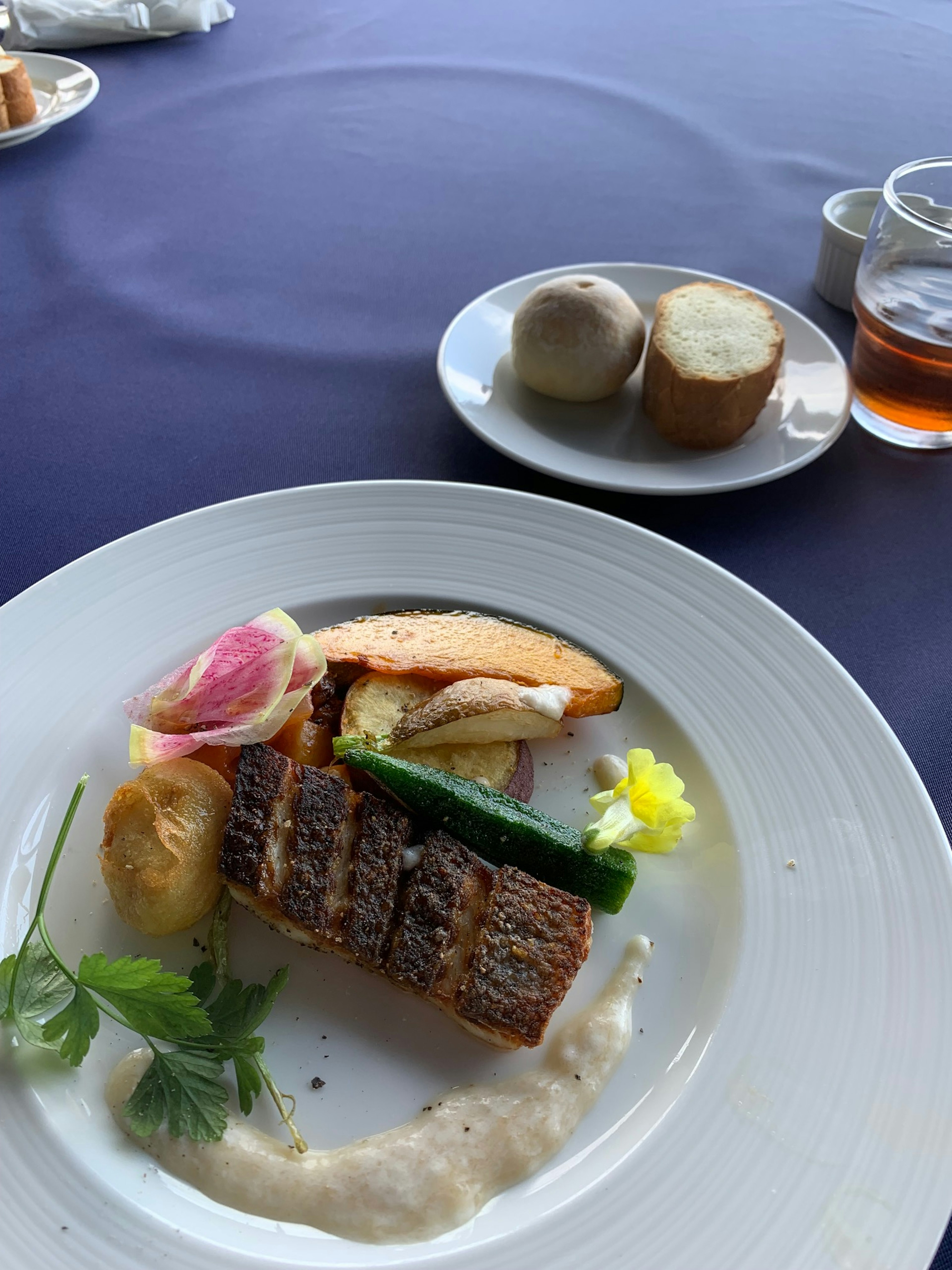 Un plato bellamente presentado con pescado a la parrilla, verduras variadas y una salsa cremosa