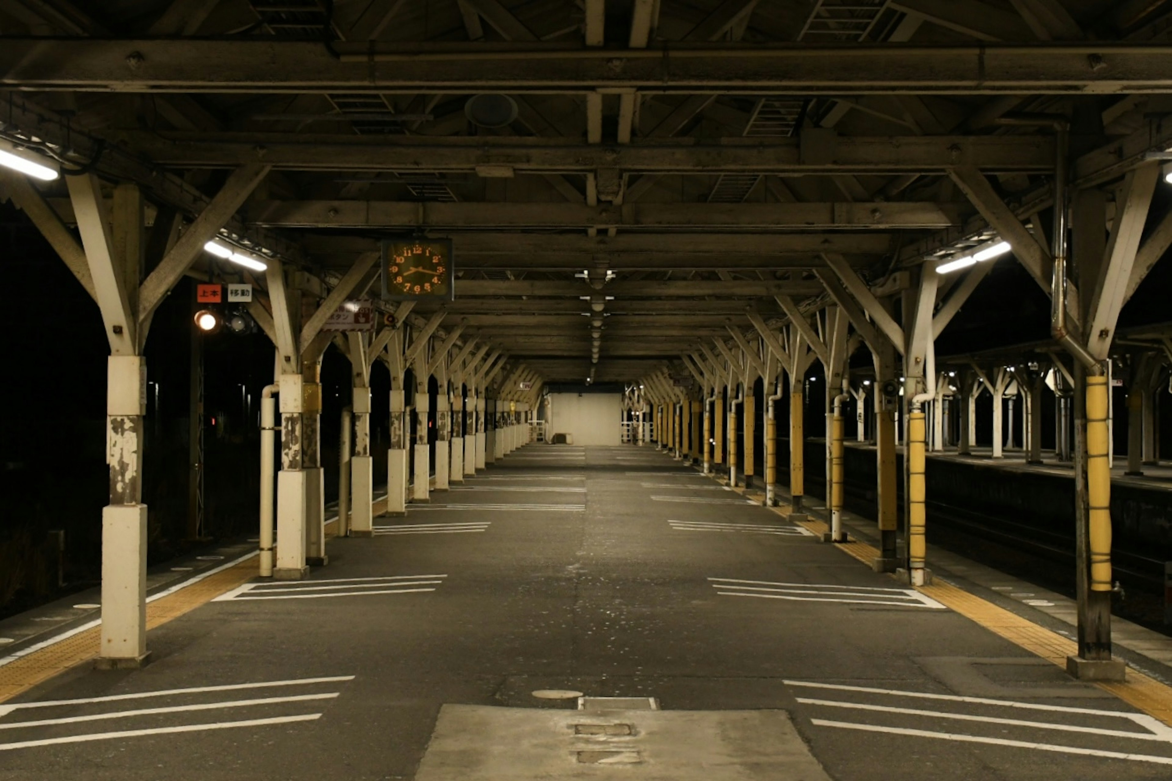 静かな駅のプラットフォーム、木の柱と照明、夜の雰囲気