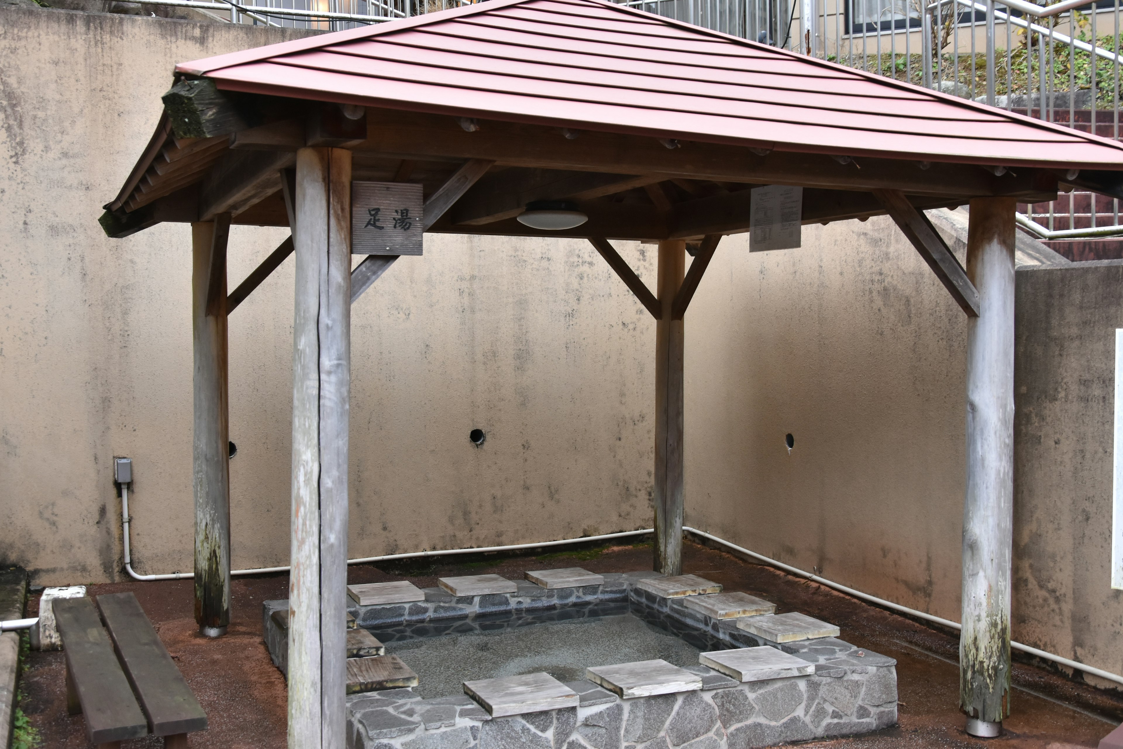 Wooden-roofed resting area with a stone hot spring basin