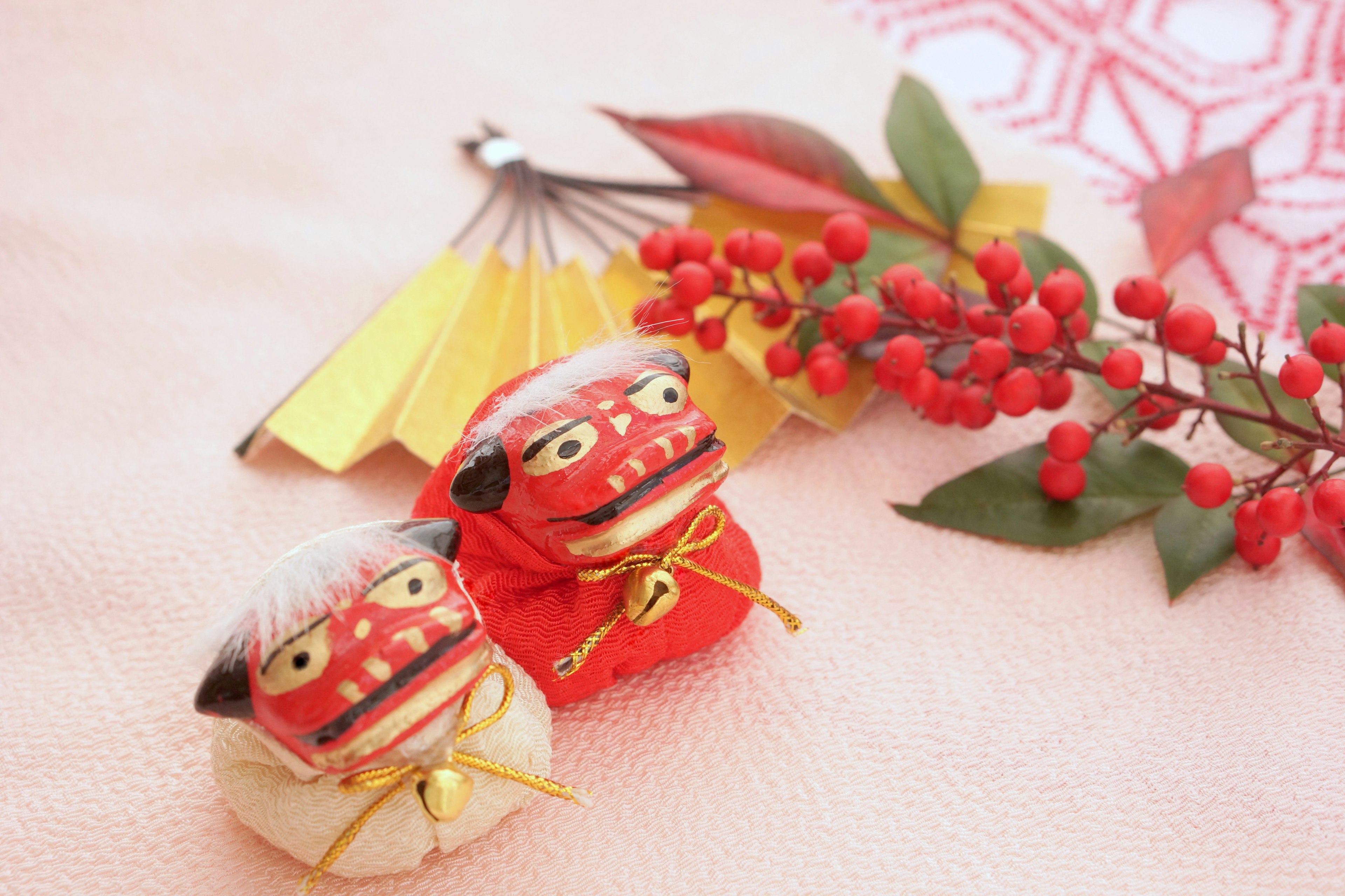 Traditional red and white dolls displayed in a Japanese setting with autumn leaves and a small fan